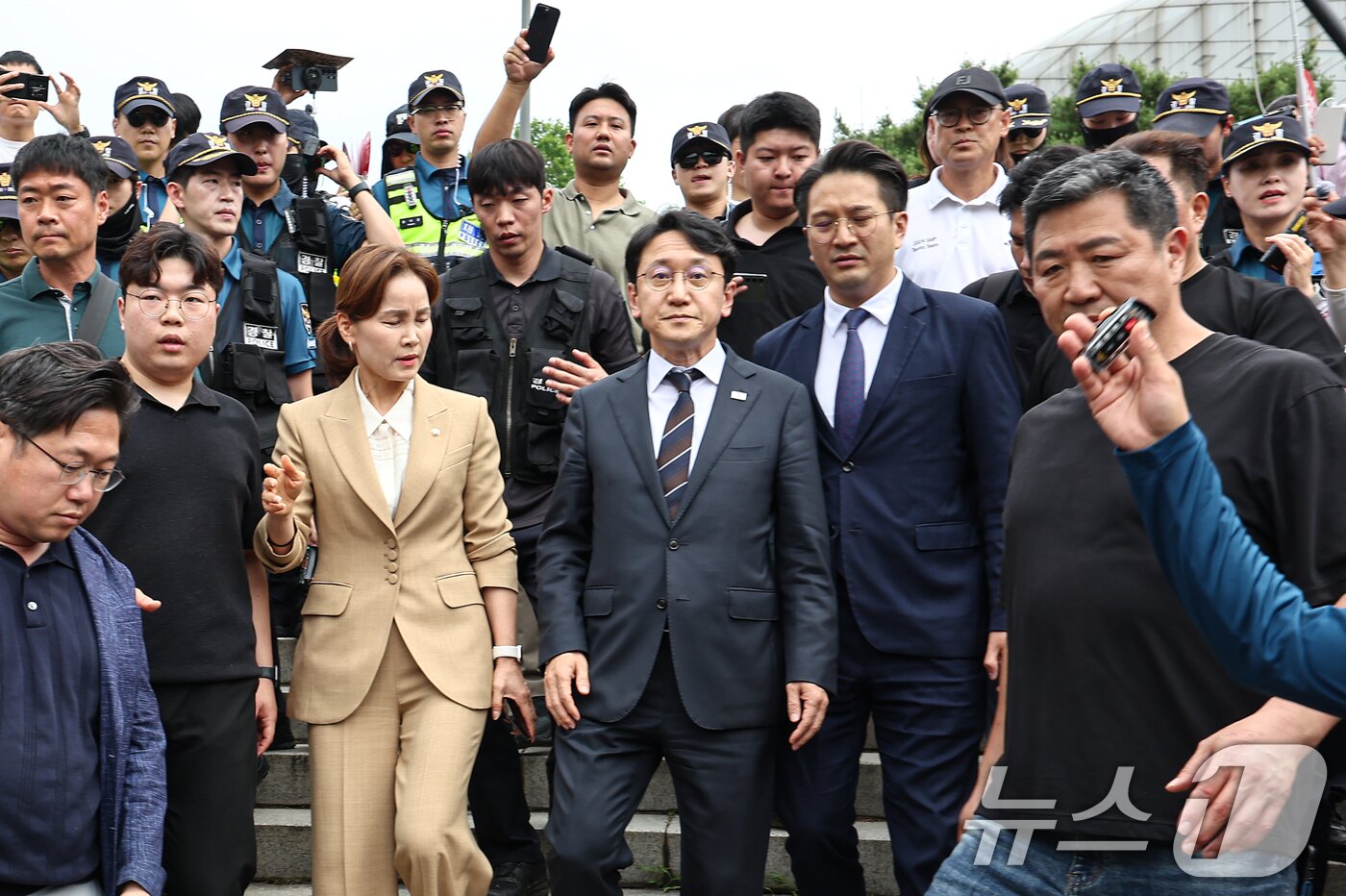 본문 이미지 - 임오경, 전용기, 천준호 더불어민주당 의원이 17일 서울 송파구 올림픽공원 핸드볼경기장 앞에서 투표용지 부족 사태를 규탄하는 시민들에게 항의를 받으며 이동하고 있다. 2026.6.17 ⓒ 뉴스1 김도우 기자
