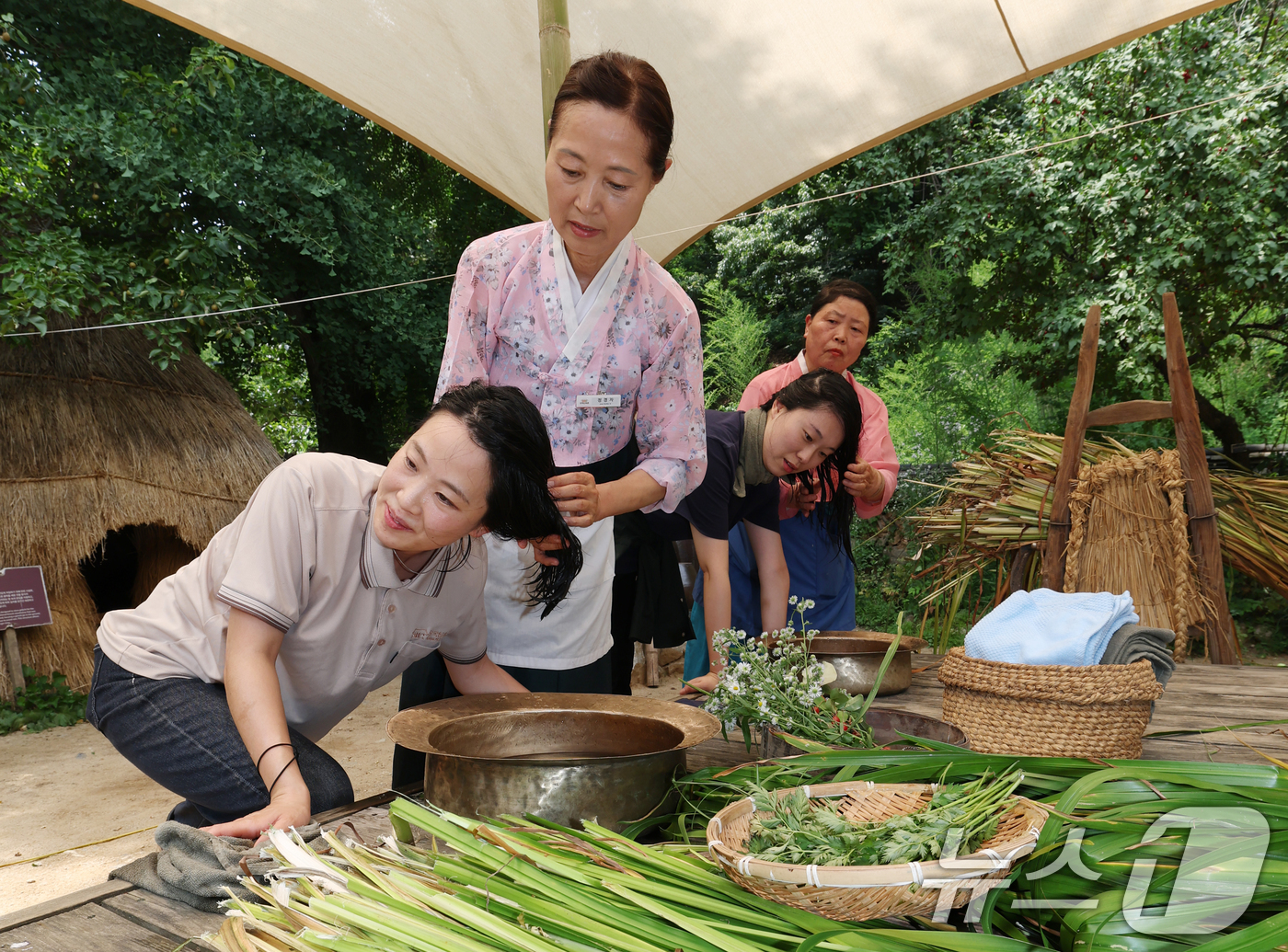 (용인=뉴스1) 김영운 기자 = 단오(음력 5월5일)를 하루 앞둔 19일 경기 용인시 기흥구 한국민속촌에서 관광객들이 창포물에 머리 감기 체험을 하고 있다. 2026.6.18/뉴스 …