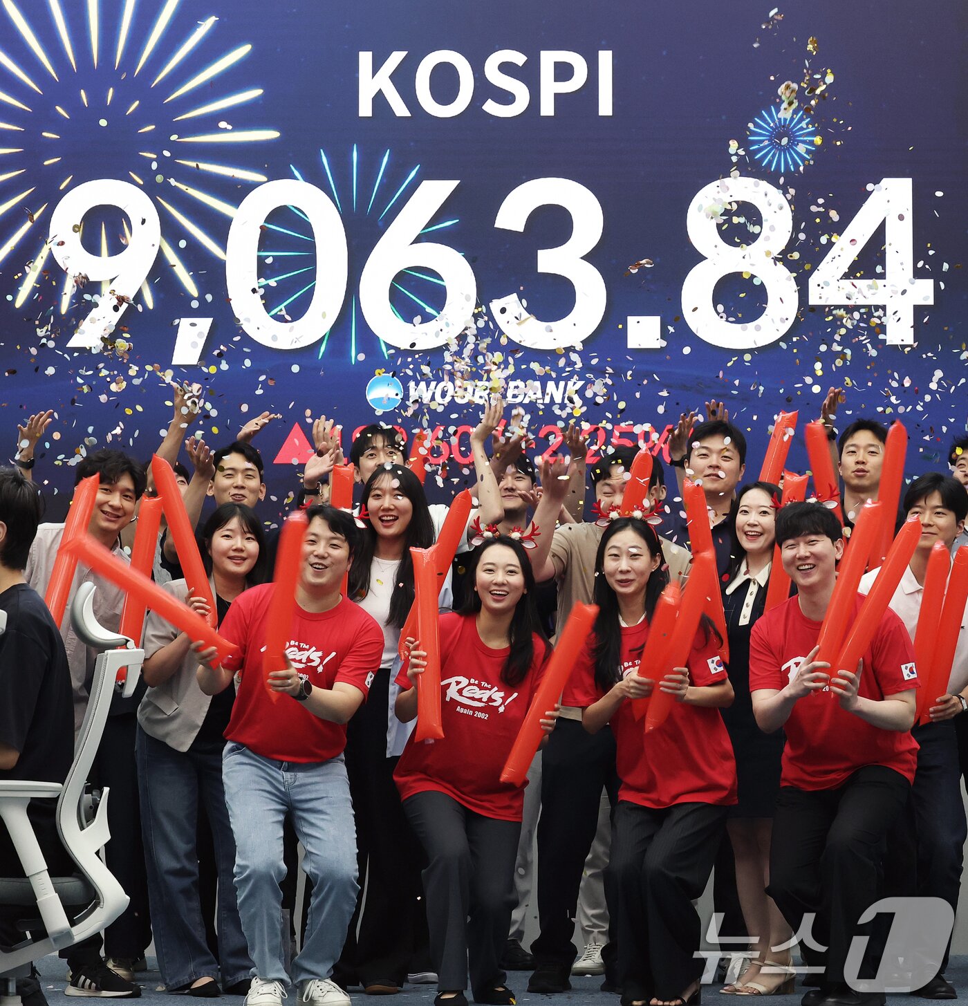 본문 이미지 - 코스피 지수가 전인미답의 9000선 고지를 돌파한 18일 오후 서울 중구 우리은행 본점 딜링룸에서 직원들이 코스피 종가를 배경으로 축하 세리머니를 하고 있다. 2026.6.18 ⓒ 뉴스1 오대일 기자