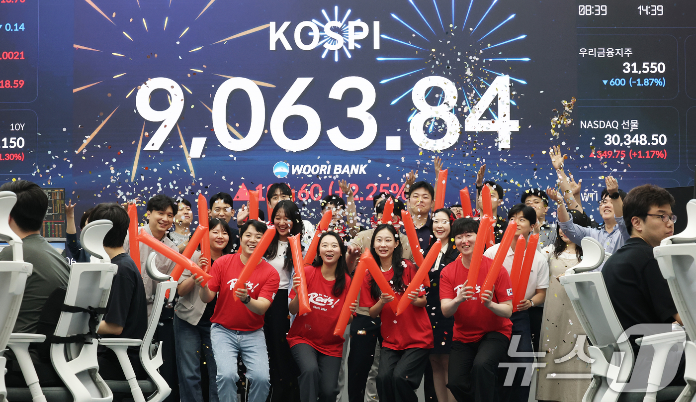 (서울=뉴스1) 오대일 기자 = 코스피 지수가 전인미답의 9000선 고지를 돌파한 18일 오후 서울 중구 우리은행 본점 딜링룸에서 직원들이 코스피 종가를 배경으로 축하 세리머니를 …