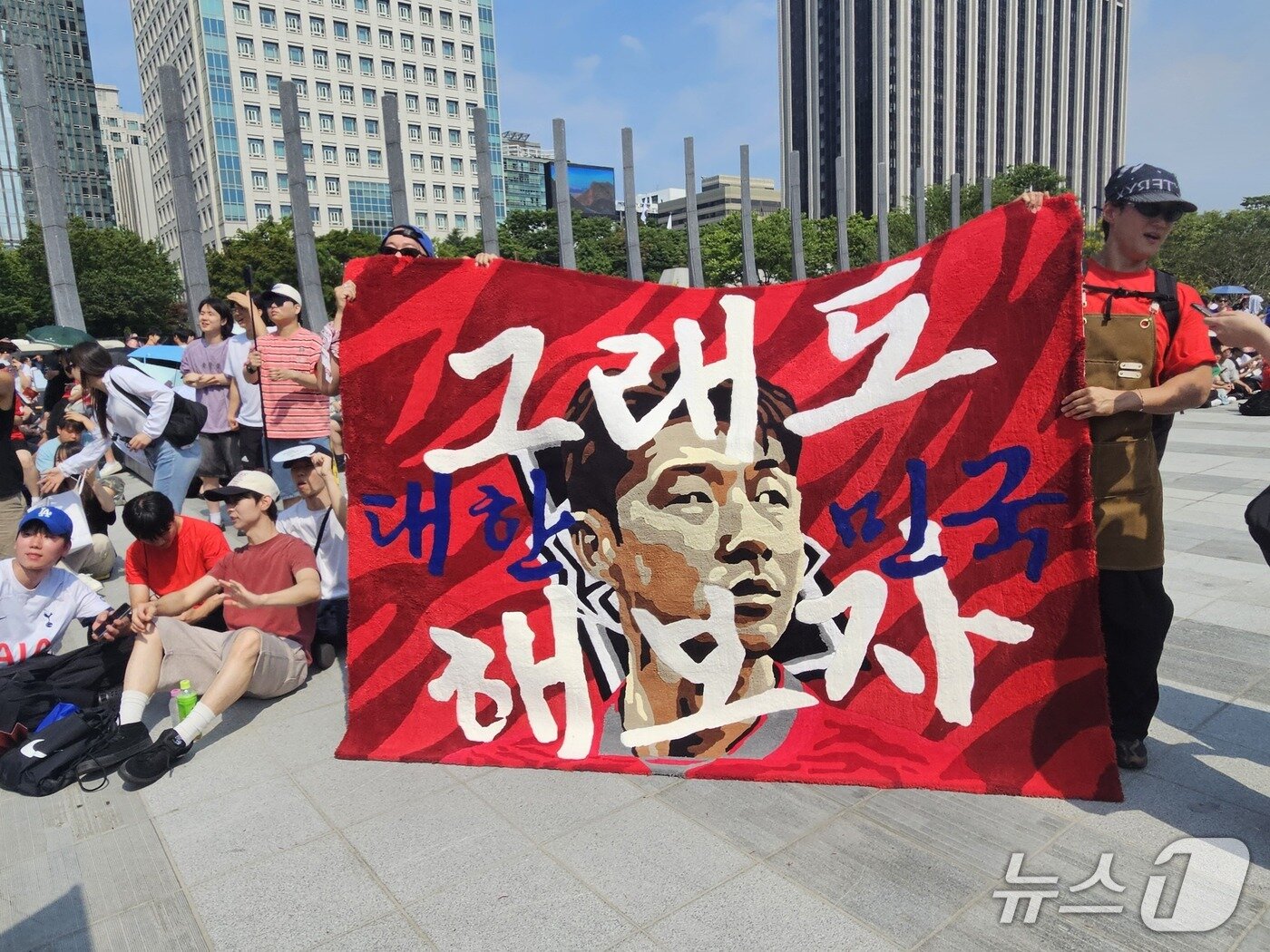본문 이미지 - 손흥민 선수 얼굴에 '그래도 대한민국 해보자'라고 적힌 대형 러그를 만들어 온 서윗(작가명·36·남) 씨의 모습. 2026.6.19 ⓒ 뉴스1 한민아 기자