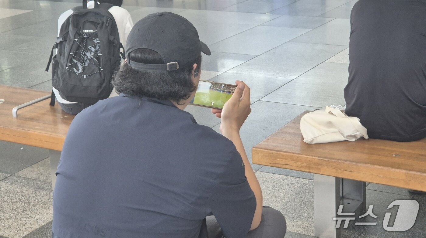본문 이미지 - 19일 울산 태화강역에서 기차를 기다리는 한 시민이 휴대전화로 월드컵 중계를 지켜보고 있다.2026.06.19.ⓒ 뉴스1 박정현 기자