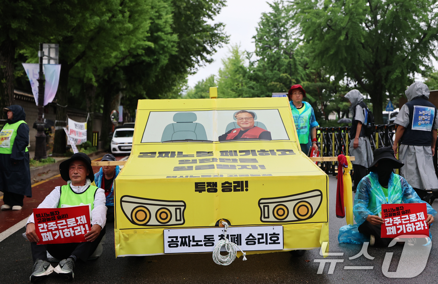 (서울=뉴스1) 오대일 기자 = 20일 오후 서울 종로구 청와대 사랑채 앞에서 열린 택시노동자 투쟁승리 공공운수노조 결의대회에서 참가자들이 '공짜노동 폐기'를 촉구하며 택시 모형을 …