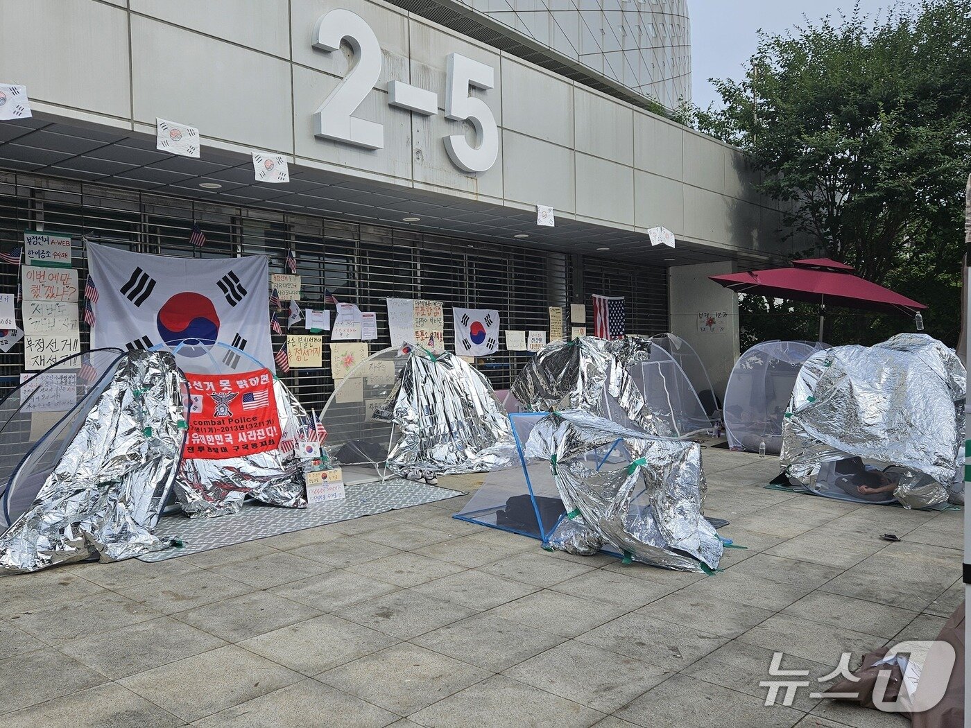 본문 이미지 - 제9회 전국동시지방선거 투표용지 부족 사태를 규탄하는 개표소 봉쇄 시위가 18일째 이어지고 있는 22일 서울 송파구 올림픽공원 핸드볼경기장 출입구 앞에 모기장 텐트가 설치돼 있다. 2026.6.22 ⓒ 윤지오 수습 기자