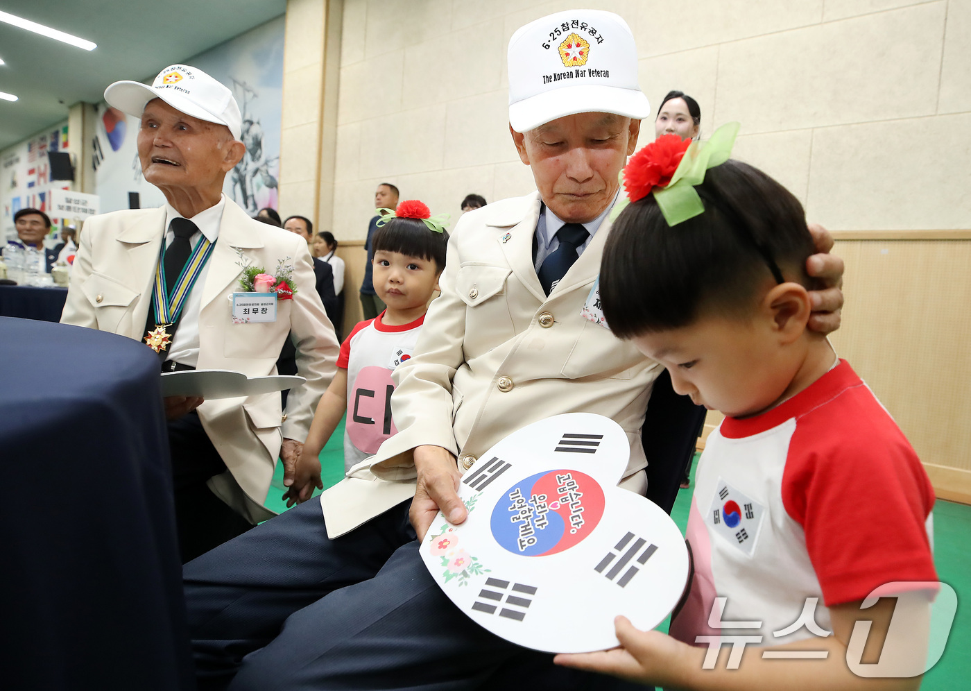 (대구=뉴스1) 공정식 기자 = 22일 대구 달성군민체육관에서 열린 6.25전쟁 제76주년 기념행사에서 한 참전유공자가 하트 모양 태극기를 선물한 어린이를 쓰다듬고 있다. 2026 …