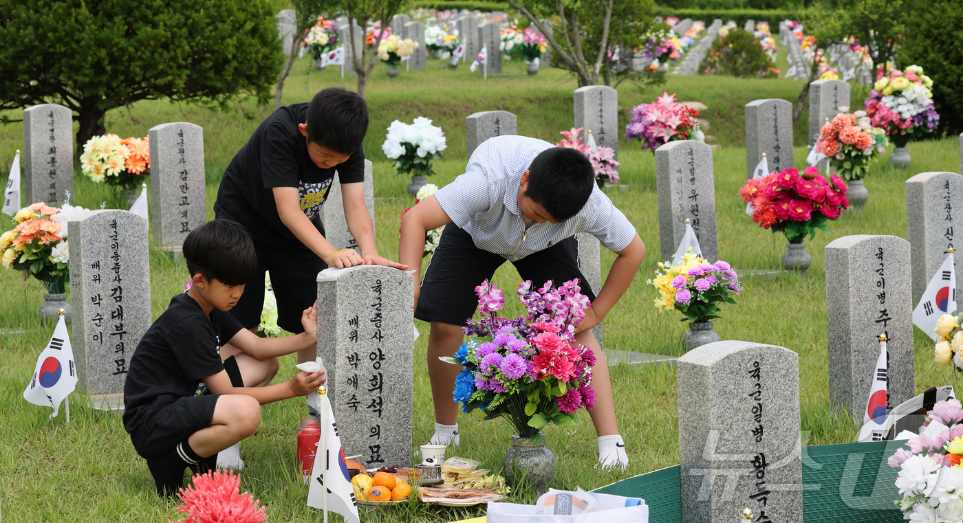 (대전=뉴스1) 김기태 기자 = 6·25 전쟁 76주년을 앞둔 23일 대전 유성구 국립대전현충원에서 유족이 묘비를 닦고 있다. 2026.6.23/뉴스1