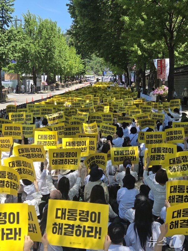 본문 이미지 - 대한간호협회 소속 간호사들이 23일 서울 종로구 청와대 분수대 인근에서 열린 '진료지원 간호사 교육체계 정상화 촉구 대회'에 참석해 "대통령이 해결하라"는 손팻말을 들고 정부의 교육체계 이원화 방침 철회를 요구하고 있다. (대한간호협회 제공)