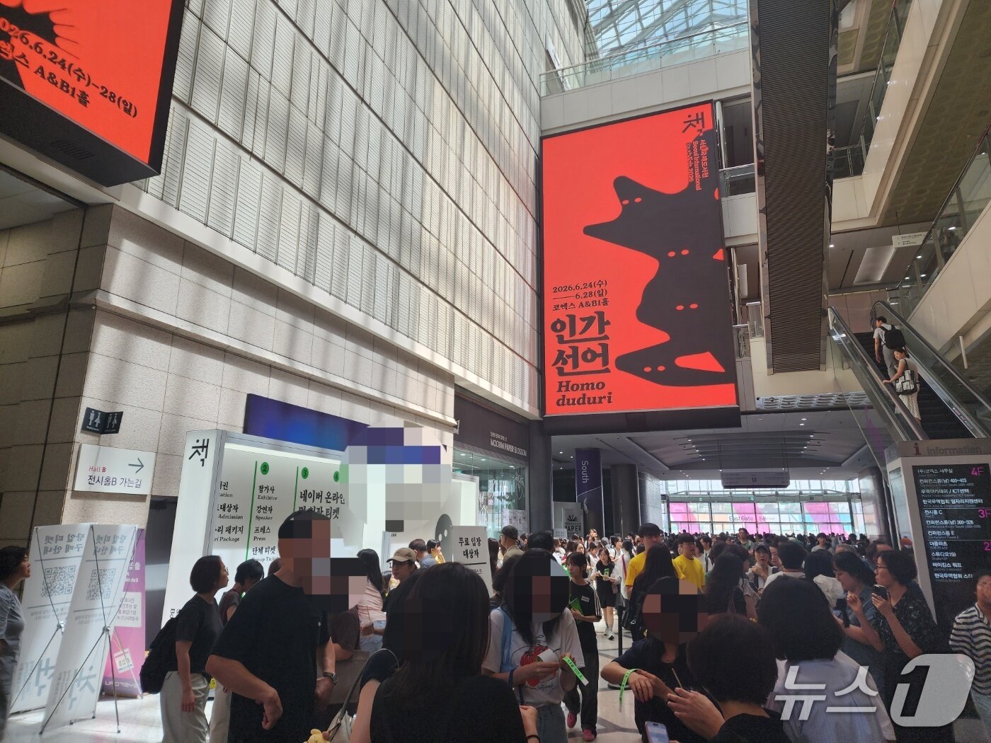 본문 이미지 - 24일 서울시 강남구 코엑스 전광판에 2026 서울국제도서전 홍보 포스터가 띄워져 있다. 홀은 도서전에 참여하려는 관객 줄로 가득 메워졌다. 2026.06.24/ⓒ 뉴스1 권진영 기자