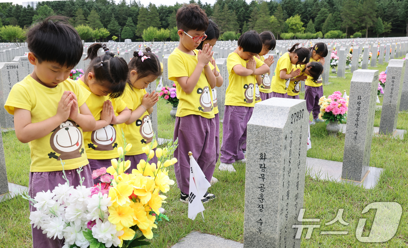 (대전=뉴스1) 김기태 기자 = 6·25 전쟁 76주년을 하루 앞둔 24일 대전 유성구 국립대전현충원 장병 1묘역에서 어린이집 원생들이 참배하고 있다. 2026.6.24/뉴스1