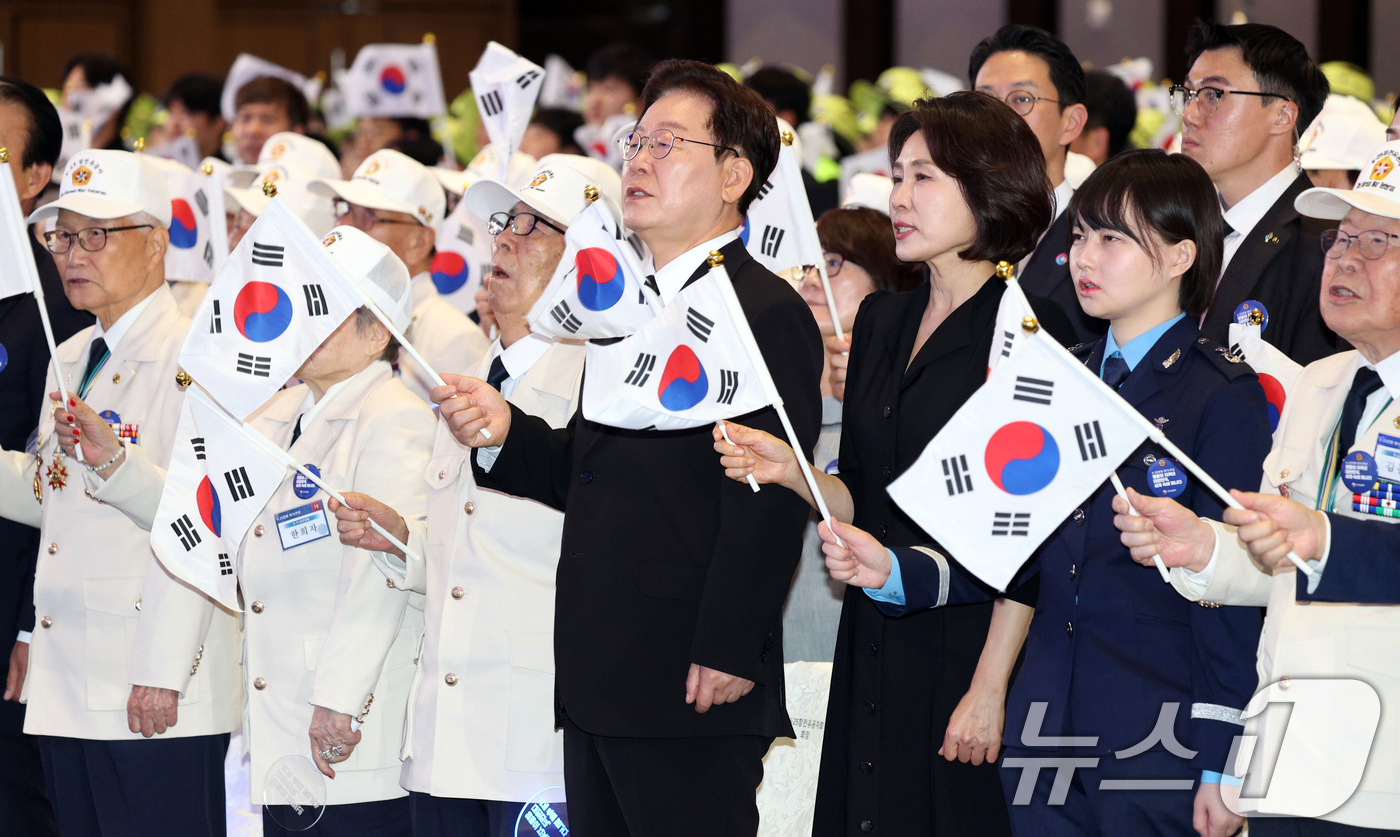 (수원=뉴스1) 허경 기자 = 이재명 대통령과 김혜경 여사가 25일 경기 수원시 영통구 수원컨벤션센터에서 열린 6·25 전쟁 제76주년 기념식에서 태극기를 흔들며 6·25 기념 노 …
