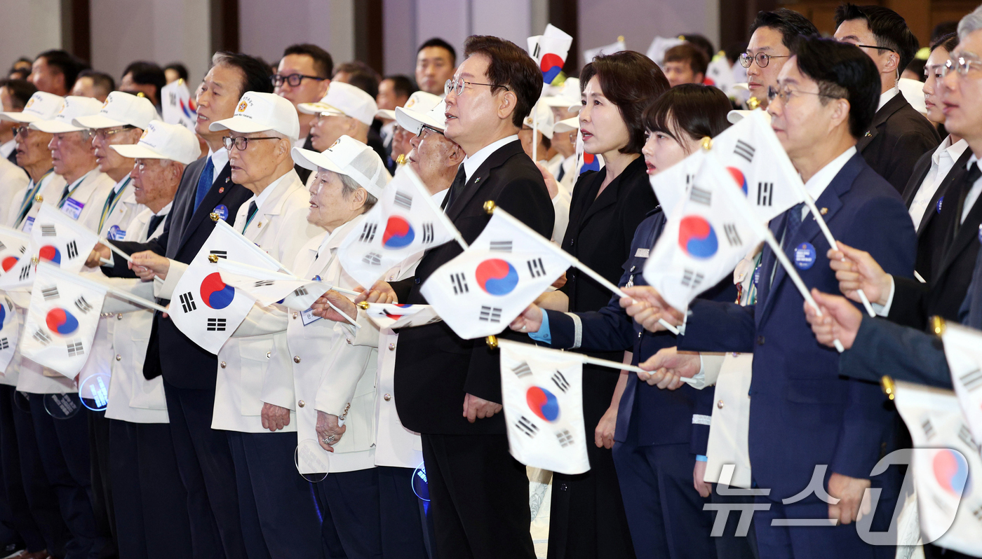 (수원=뉴스1) 허경 기자 = 이재명 대통령과 김혜경 여사가 25일 경기 수원시 영통구 수원컨벤션센터에서 열린 6·25 전쟁 제76주년 기념식에서 태극기를 흔들며 6·25 기념 노 …