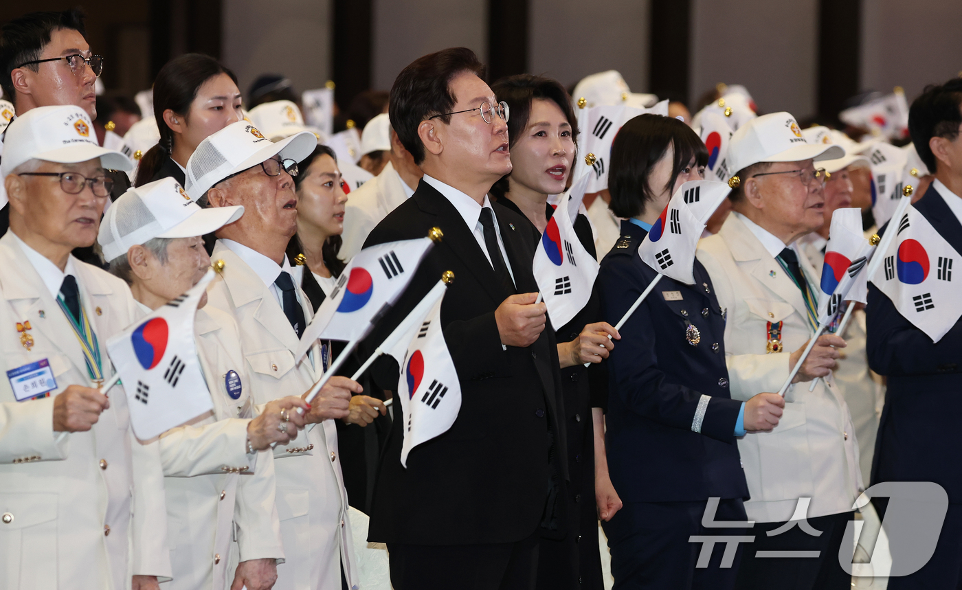 (수원=뉴스1) 허경 기자 = 이재명 대통령과 김혜경 여사가 25일 경기 수원시 영통구 수원컨벤션센터에서 열린 6·25 전쟁 제76주년 기념식에서 태극기를 흔들며 6·25 기념 노 …
