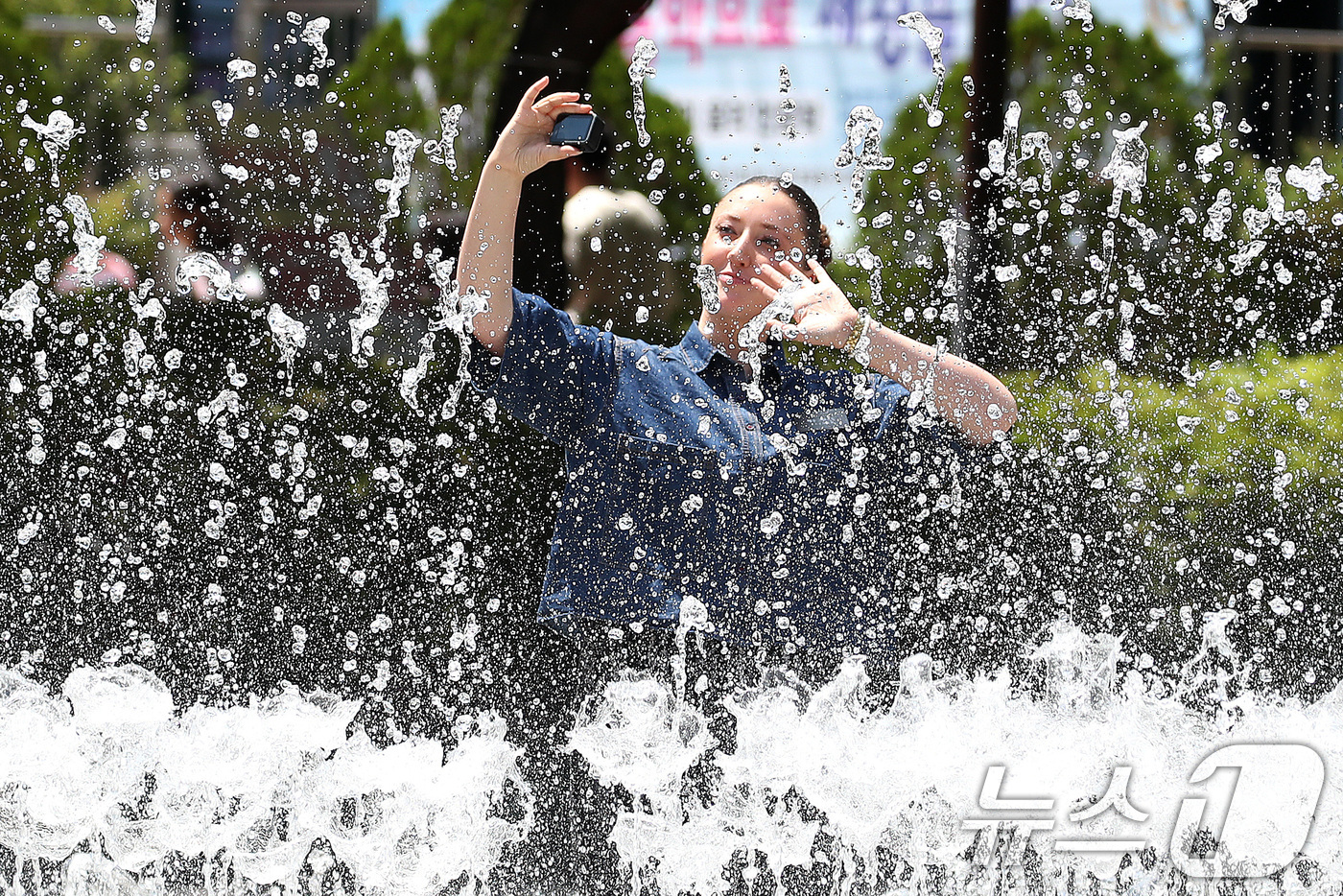 (대구=뉴스1) 공정식 기자 = 구름 사이로 해가 나오며 더위가 찾아온 26일 오후 대구 서구 평리공원에서 한 외국인이 바닥분수 물줄기 사이를 오가며 기념사진을 찍고 있다. 202 …