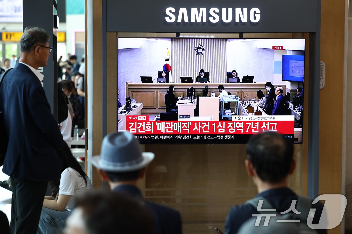 본문 이미지 - 26일 오후 서울 용산구 서울역 대합실에서 각종 고가 귀금속과 함께 인사, 이권 청탁을 받은 혐의로 특정범죄 가중처벌법상 알선수재 혐의로 기소된 김건희 여사의 1심 선고 생중계가 나오고 있다. 이날 재판부는 김건희 여사에게 징역 7년을 선고했다. 2026.6.26 ⓒ 뉴스1 최지환 기자