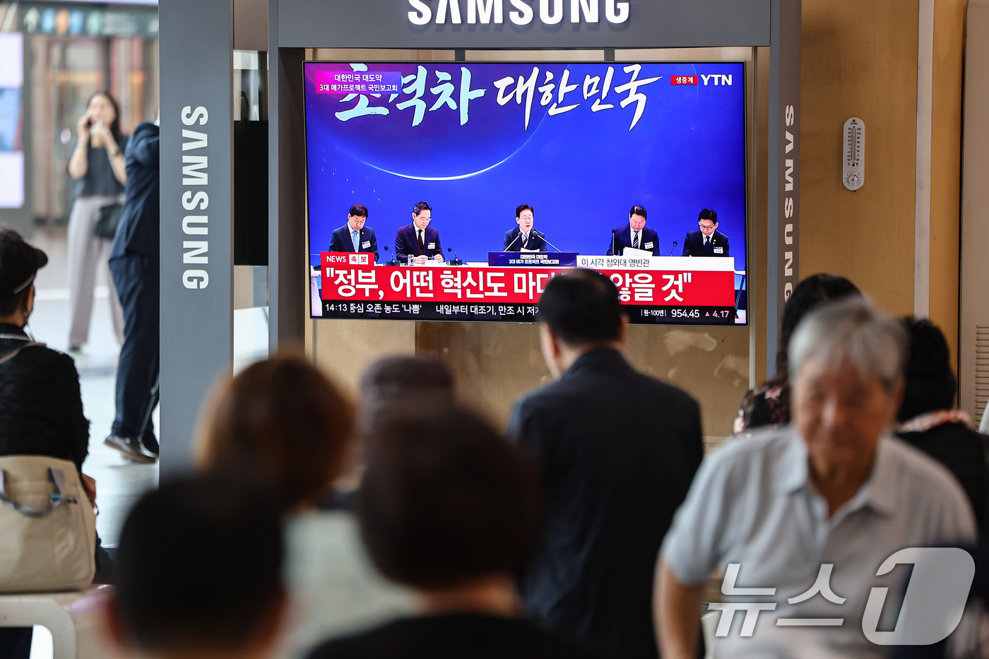(서울=뉴스1) 김도우 기자 = 29일 서울역에서 시민들이 이재명 대통령이 주재하는 3대 메가프로젝트 국민보고회를 TV 생중계를 통해 시청하고 있다. 2026.6.29/뉴스1