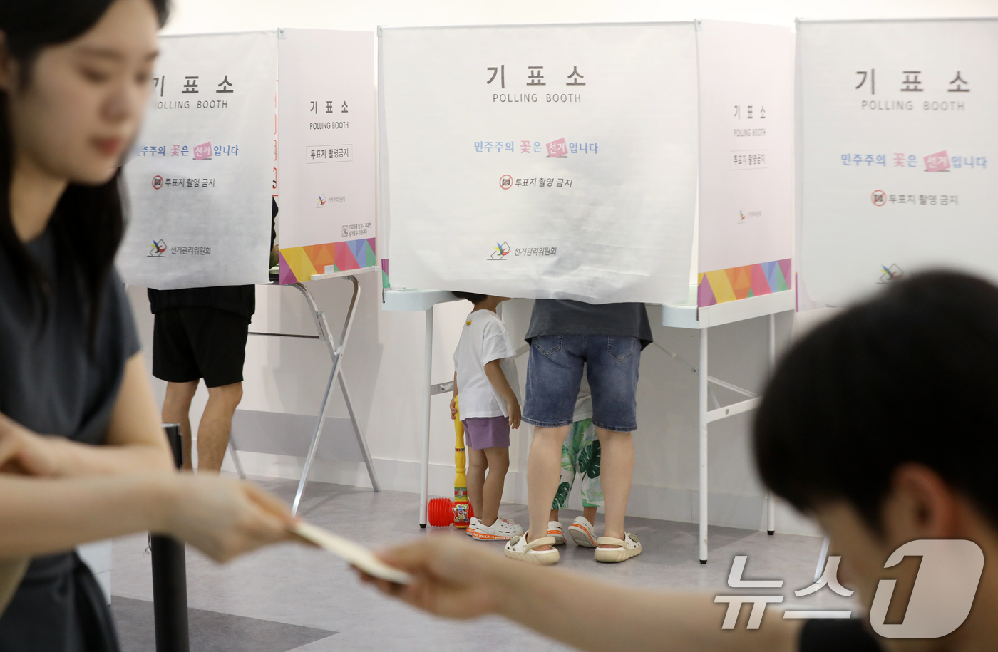 (부산=뉴스1) 윤일지 기자 = 제9회 전국동시지방선거 및 국회의원 재·보궐선거일인 3일 부산 부산진구청에 마련된 부암제1동제4투표소에서 아이들이 엄마가 투표하는 모습을 지켜보고 …