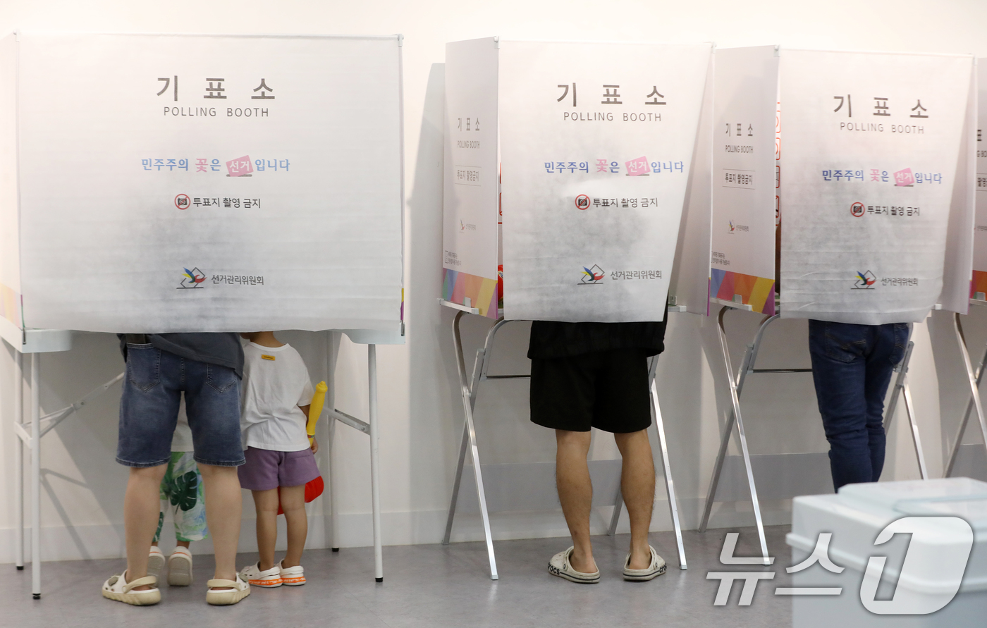 (부산=뉴스1) 윤일지 기자 = 제9회 전국동시지방선거 및 국회의원 재·보궐선거일인 3일 부산 부산진구청에 마련된 부암제1동제4투표소에서 아이들이 엄마가 투표하는 모습을 지켜보고 …
