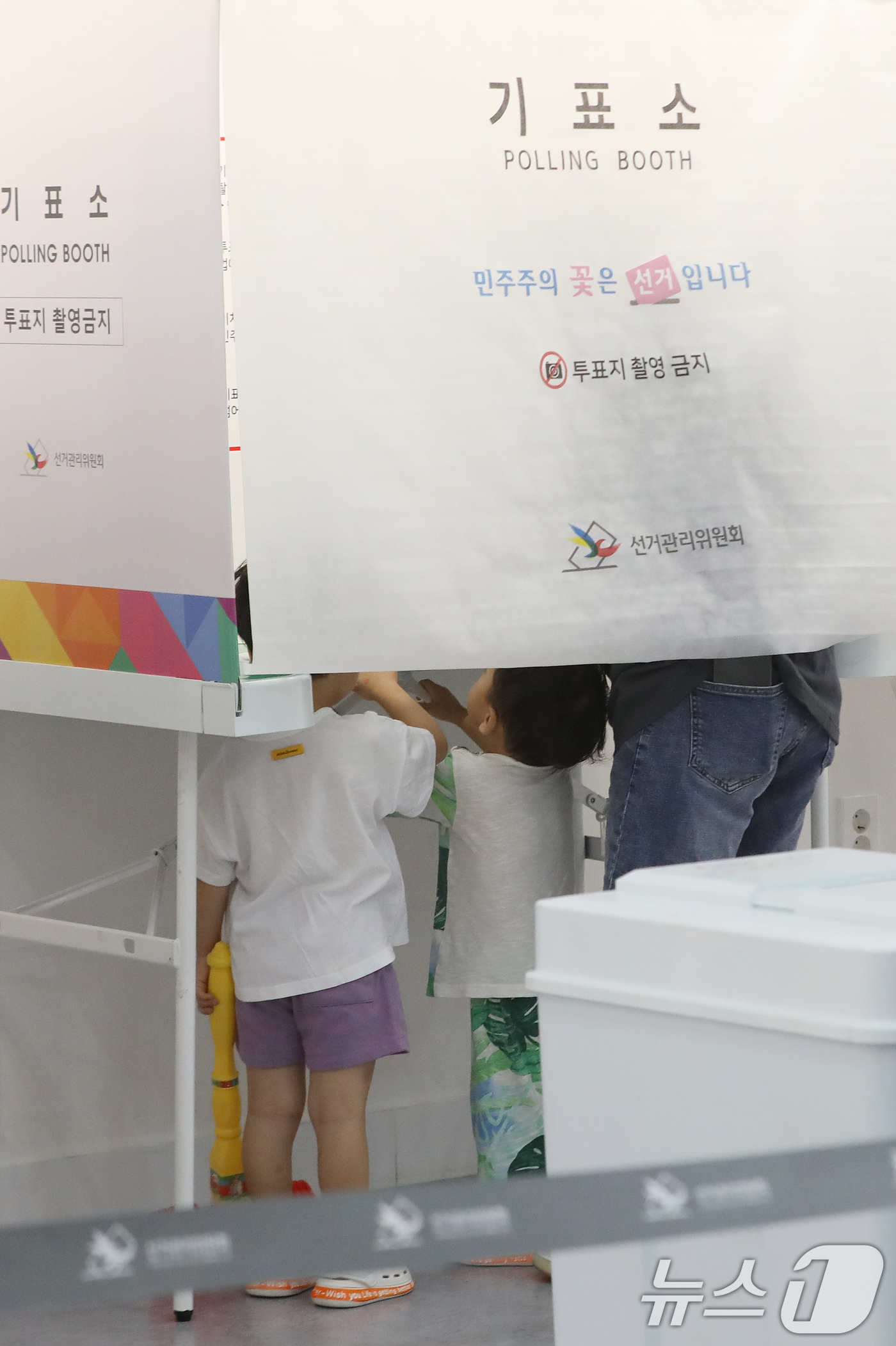 (부산=뉴스1) 윤일지 기자 = 제9회 전국동시지방선거 및 국회의원 재·보궐선거일인 3일 부산 부산진구청에 마련된 부암제1동제4투표소에서 아이들이 엄마가 투표하는 모습을 지켜보고 …