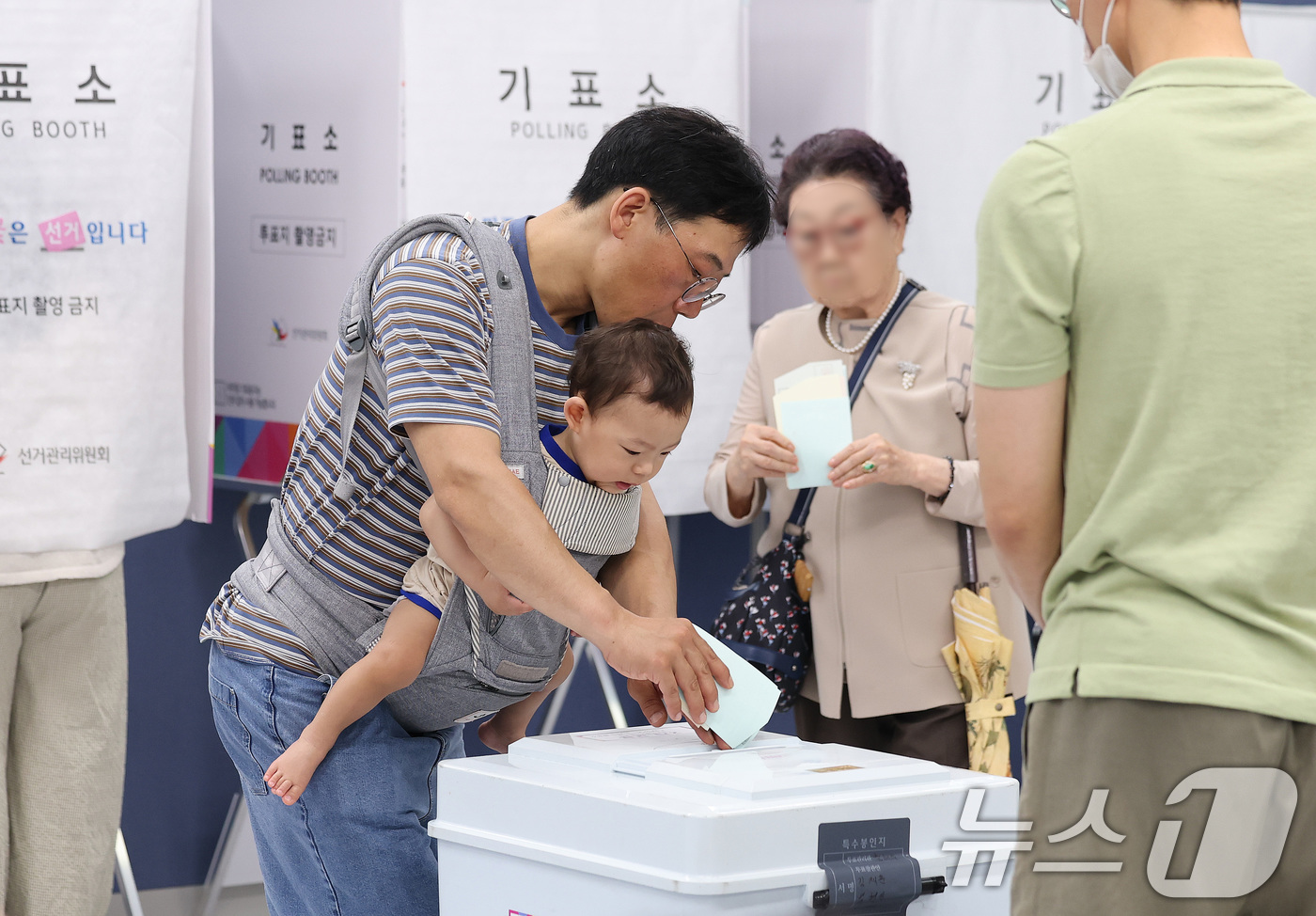 (서울=뉴스1) 박지혜 기자 = 제9회 전국동시지방선거일인 3일 서울 강남구 강남구청에 마련된 삼성2동 제5투표소에서 한 시민이 아기를 아기띠에 안은 채 소중한 한 표를 행사하고 …