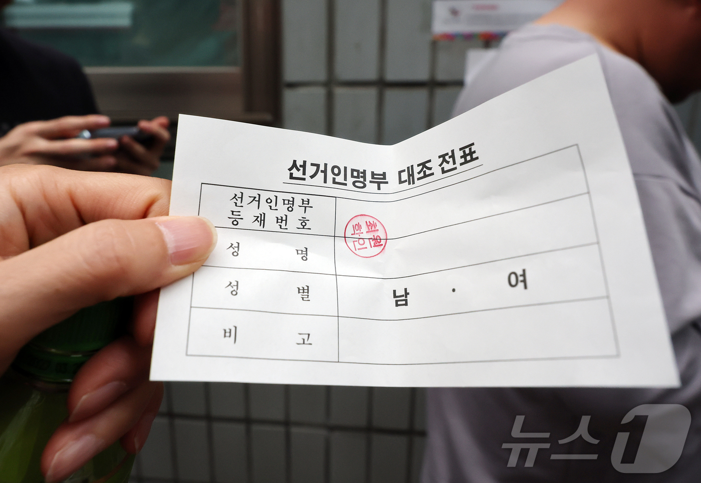 (서울=뉴스1) 김진환 기자 = 제9회 전국동시지방선거일인 3일 서울 송파구 잠실2동 6투표소에서 투표용지 부족으로 대기하던 한 유권자가 마감시간 후 선거인명부 대조 전표를 들어보 …
