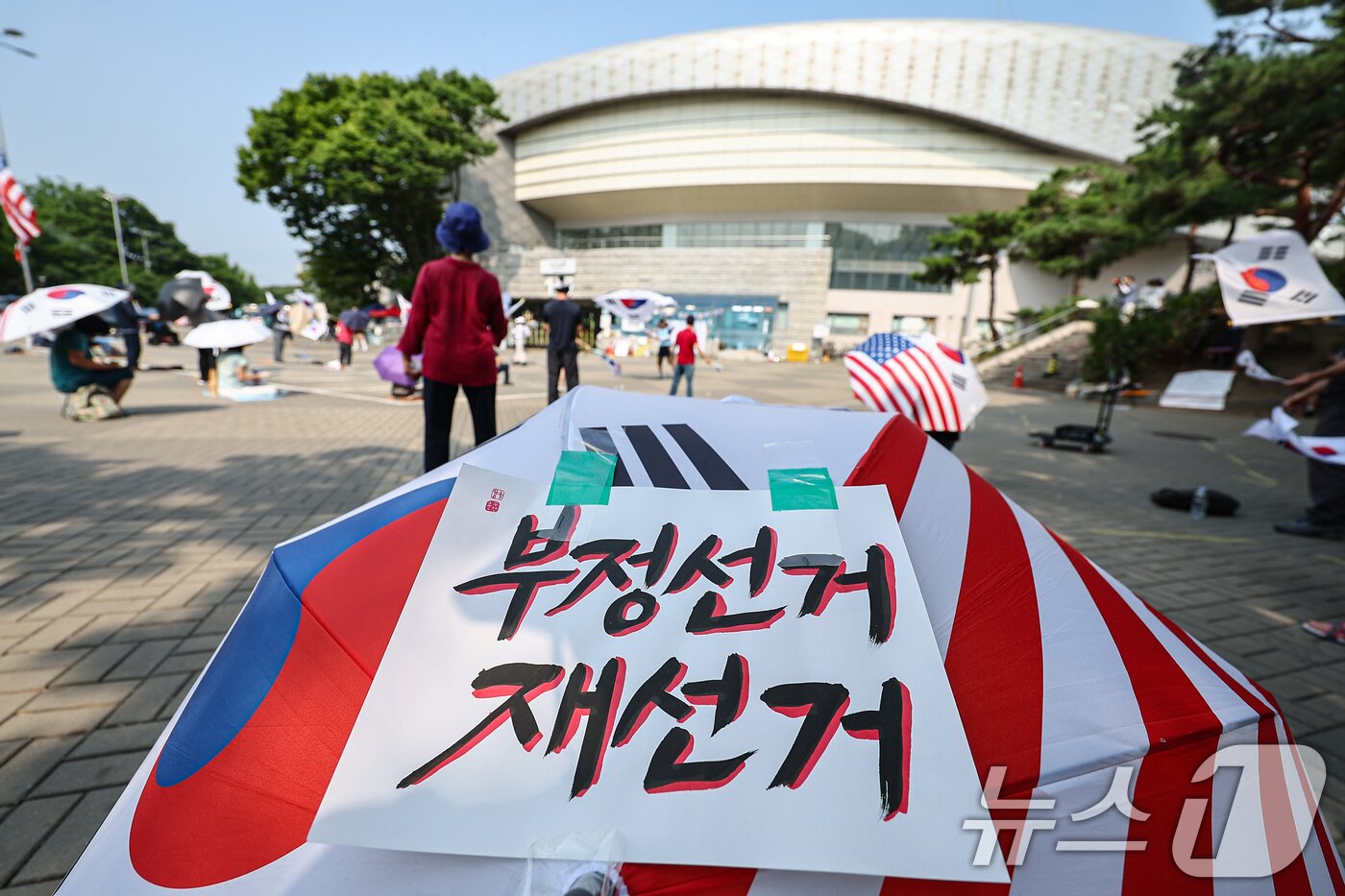 본문 이미지 - 6·3 지방선거 투표용지 부족사태로 인한 '잠실 봉쇄시위'가 26일째를 맞은 30일 서울 송파구 올림픽공원 핸드볼경기장 인근에서 참가자들이 재선거를 요구하는 구호를 외치고 있다. 2026.6.30 ⓒ 뉴스1 김도우 기자