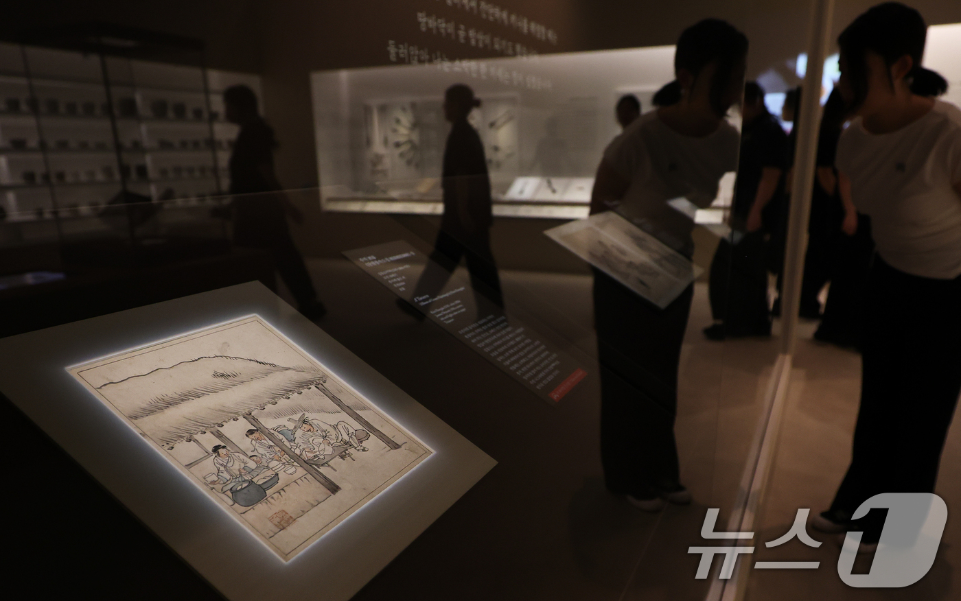 (서울=뉴스1) 오대일 기자 = 30일 서울 용산구 국립중앙박물관에서 열린 ‘우리들의 밥상’ 특별전 언론공개회에서 관계자가 단원 김홍도의 단원풍속도첩 중 '주막'을 살펴보고 있다. …