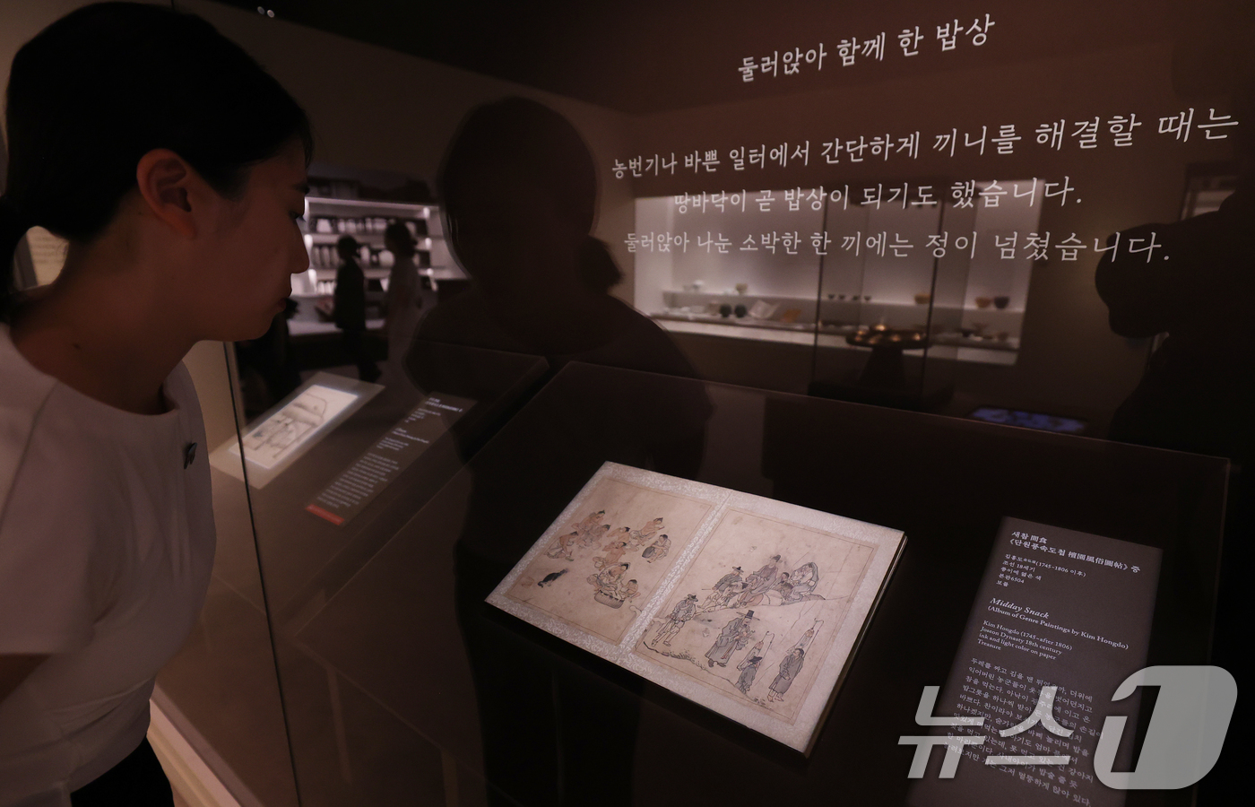 (서울=뉴스1) 오대일 기자 = 30일 서울 용산구 국립중앙박물관에서 열린 ‘우리들의 밥상’ 특별전 언론공개회에서 관계자가 단원 김홍도의 단원풍속도첩 중 '새참'을 살펴보고 있다. …