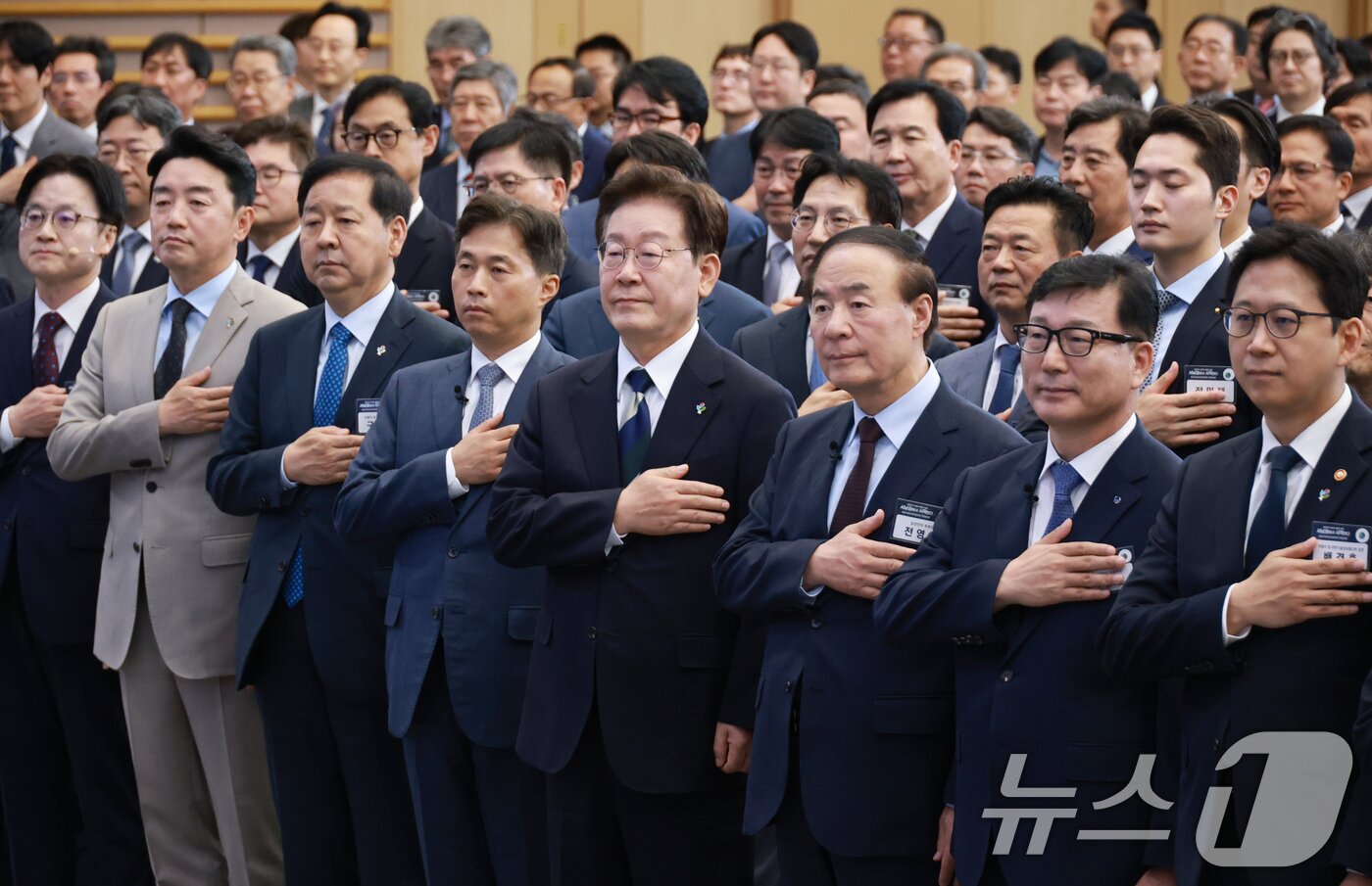 본문 이미지 - 이재명 대통령이 30일 광주 김대중 컨벤션센터에서 열린 서남권 첨단산업 발전비전 국민보고회에서 국민의례를 하고 있다. 앞줄 왼쪽부터 김정관 산업통상부 장관, 강훈식 비서실장, 구윤철 부총리 겸 재정경제부 장관, 곽노정 SK하이닉스 대표, 이재명 대통령, 전영현 삼성전자 부회장, 이진안 앰코테크놀로지코리아 대표, 배경훈 부총리 겸 과기정통부 장관. (청와대통신사진기자단) 2026.6.30 ⓒ 뉴스1 이재명 기자