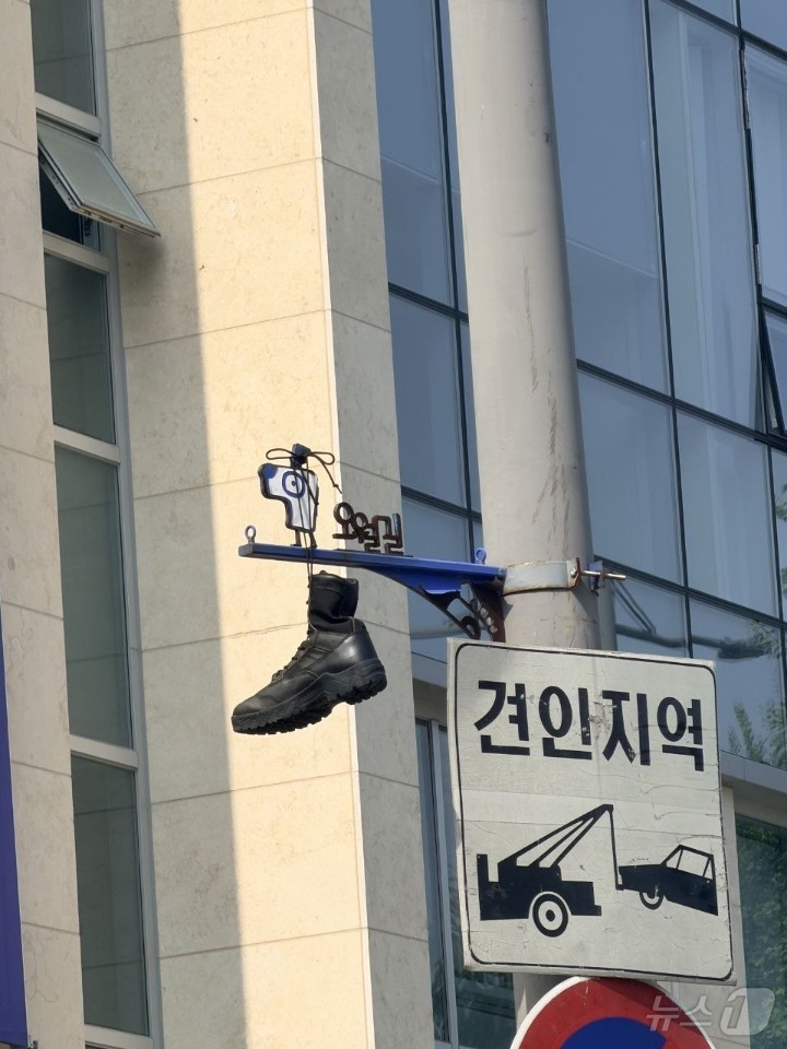 (광주=뉴스1) 전원 기자 = 30일 광주 동구 대인동의 한 교차로에 설치된 오월길을 안내하는 표지판에 군화가 걸려 있다.5.18기념재단과 광주시는 군화를 수거하는 한편 누가, 어 …
