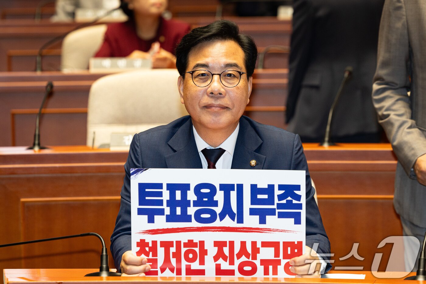 본문 이미지 - 송언석 국민의힘 원내대표가 4일 서울 여의도 국회에서 열린 긴급 의원총회에 참석해 '투표용지 부족 철저한 진상규명'이라고 쓰여진 손팻말을 취재진을 향해 들어보이고 있다. 2026.6.4 ⓒ 뉴스1 유승관 기자