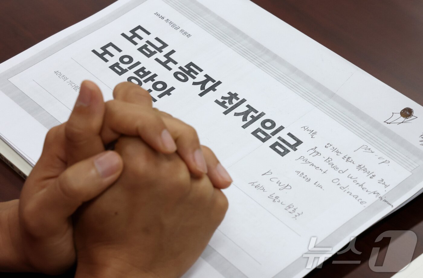 본문 이미지 - 박정훈 근로자위원이 지난 4일 세종시 정부세종청사 최저임금위원회에서 열린 2027년도 최저임금위원회 3차 전원회의에 참석하여 도급노동자 최저임금 도입방안 자료위에 두손을 모은채 발언을 듣고 있다.ⓒ 뉴스1 김기남 기자