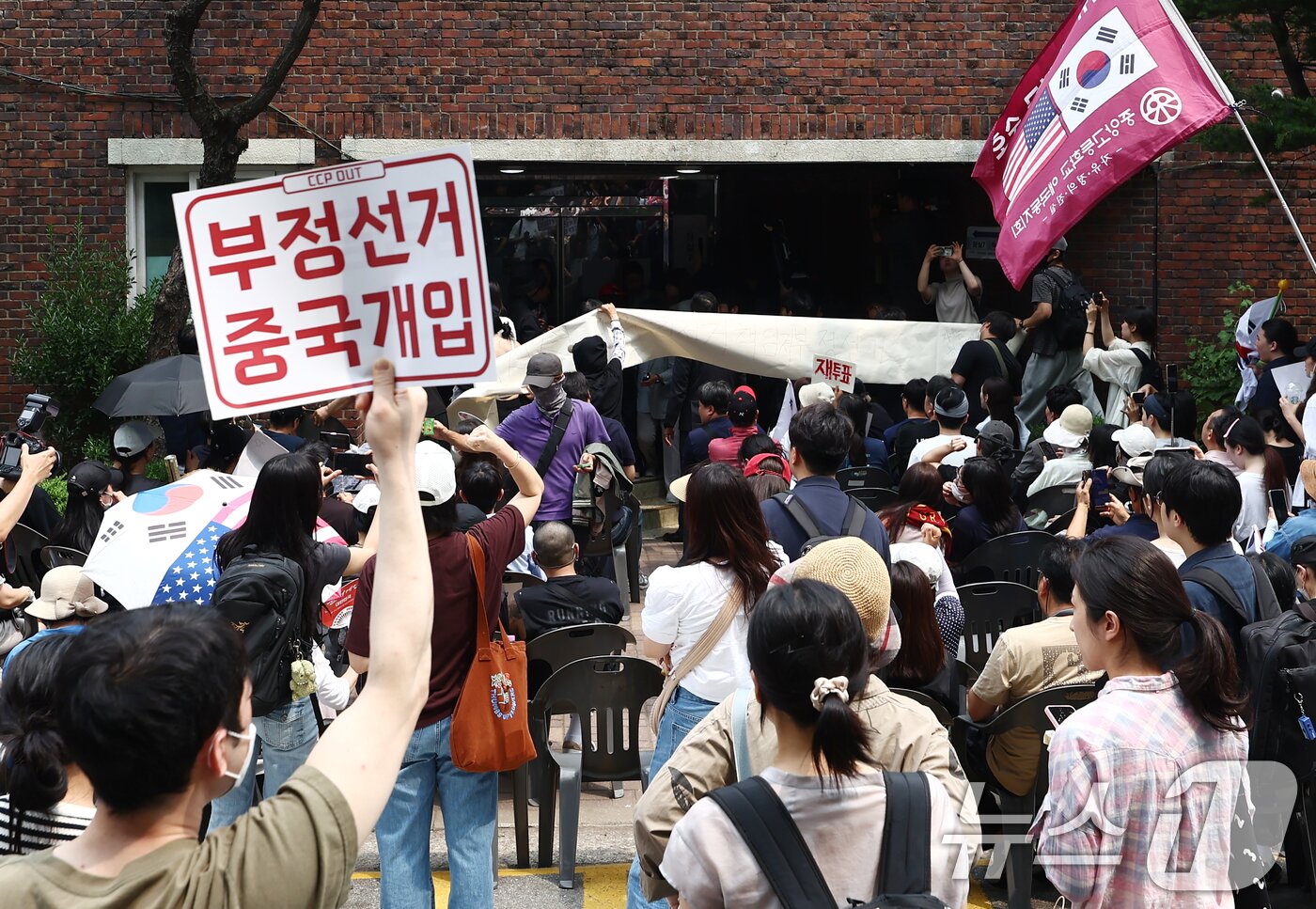 본문 이미지 - 지난 4일 제9회 전국동시지방선거 및 국회의원 재·보궐선거 투표함 이송이 지연되고 있는 서울 송파구 잠실7동 제2투표소에서 시위대와 일부 주민들이 부정선거를 외치며 입구를 봉쇄하고 있다. 2026.6.4 ⓒ 뉴스1 김민지 기자
