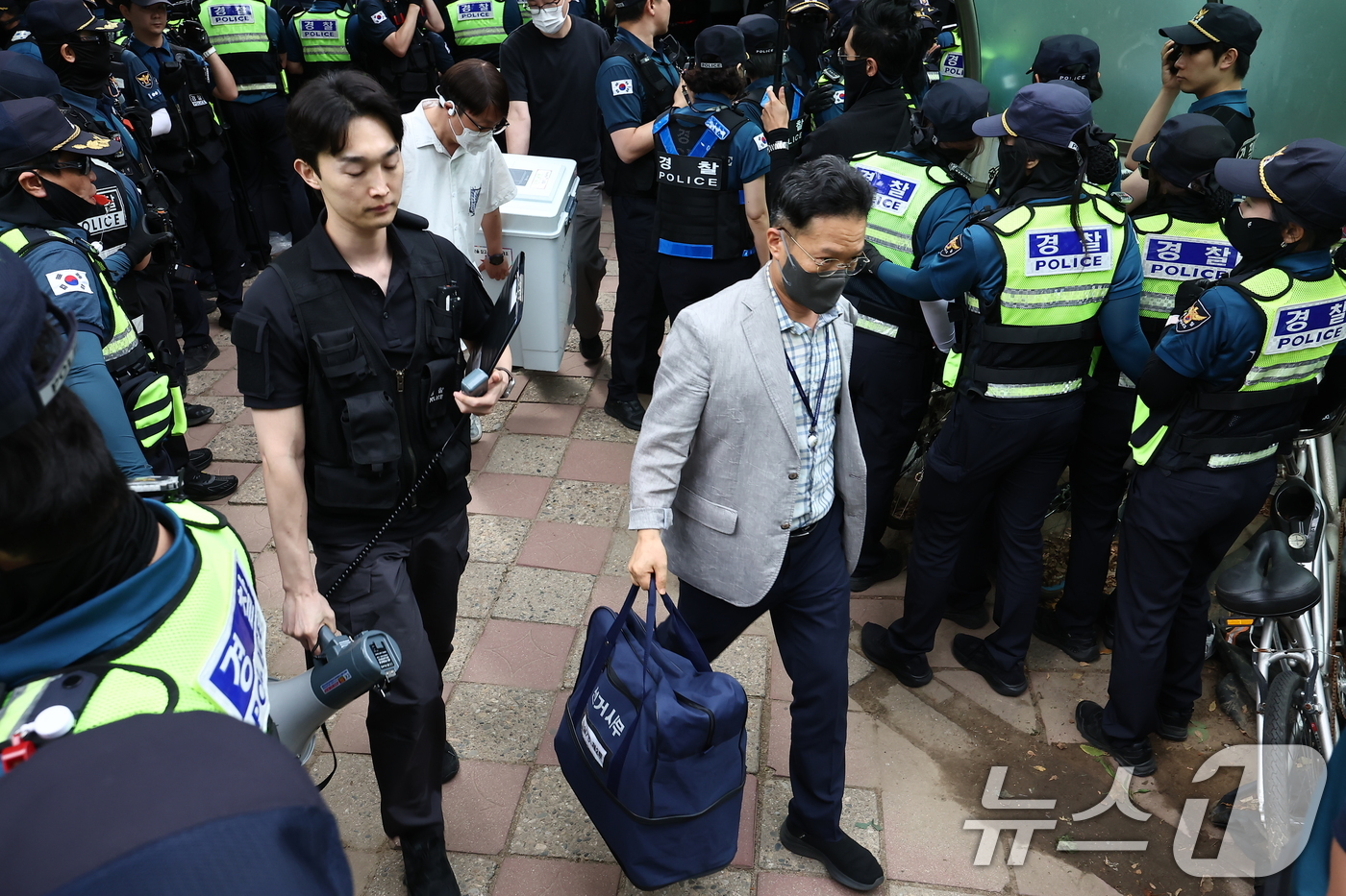 (서울=뉴스1) 김도우 기자 = 5일 '투표용지 부족' 사태가 발생한 서울 송파구 잠실7동 제2투표소 앞에서 경찰과 서울시선관위 관계자들이 투표함을 이송하고 있다. 2026.6.5 …