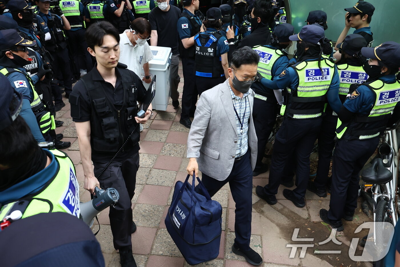 본문 이미지 - 5일 '투표용지 부족' 사태가 발생한 서울 송파구 잠실7동 제2투표소 앞에서 경찰과 서울시선관위 관계자들이 투표함을 이송하고 있다. 2026.6.5 ⓒ 뉴스1 김도우 기자