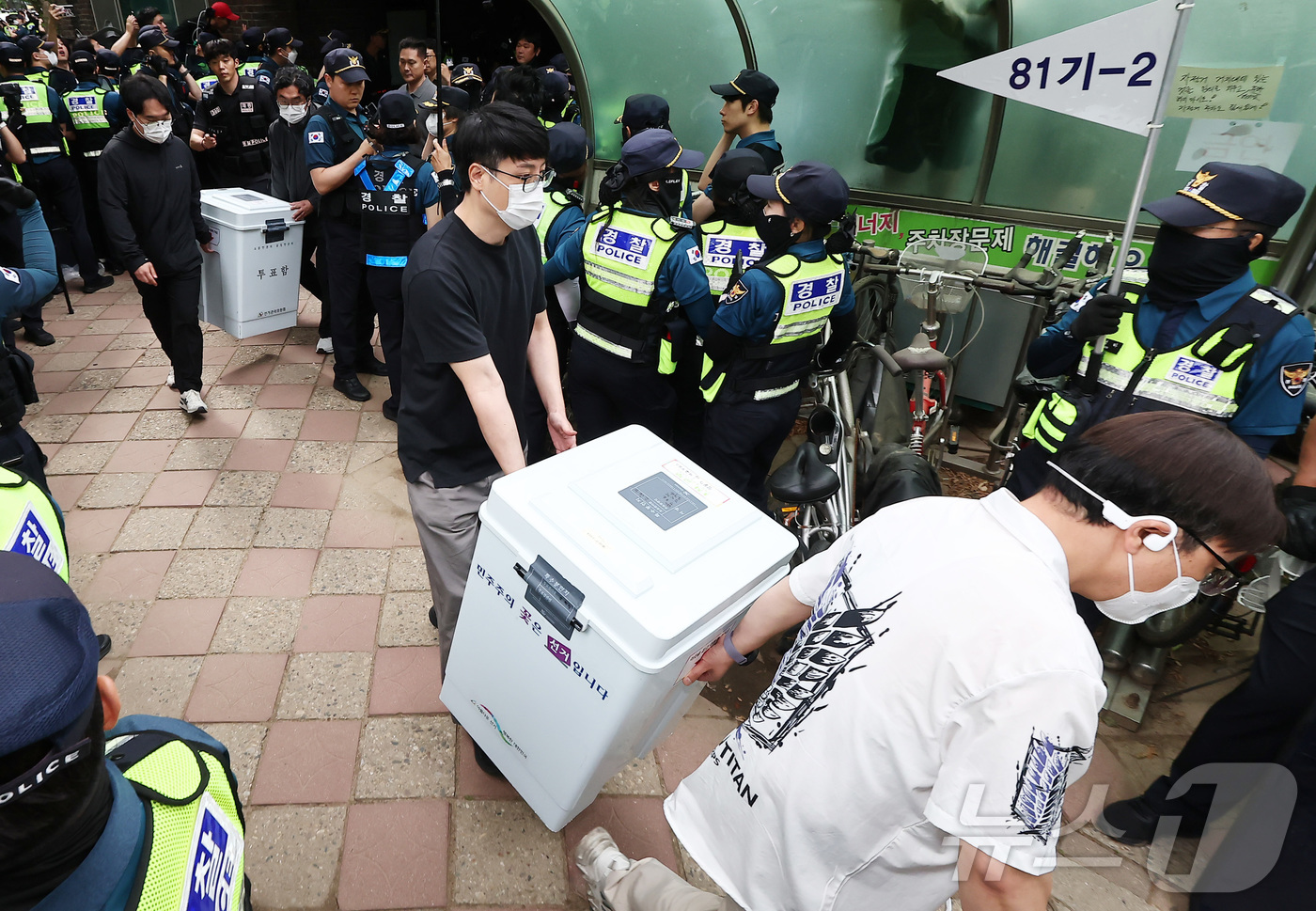 (서울=뉴스1) 김도우 기자 = 5일 '투표용지 부족' 사태가 발생한 서울 송파구 잠실7동 제2투표소 앞에서 서울시선관위 관계자들이 투표함을 이송하고 있다.  2026.6.5/뉴스 …