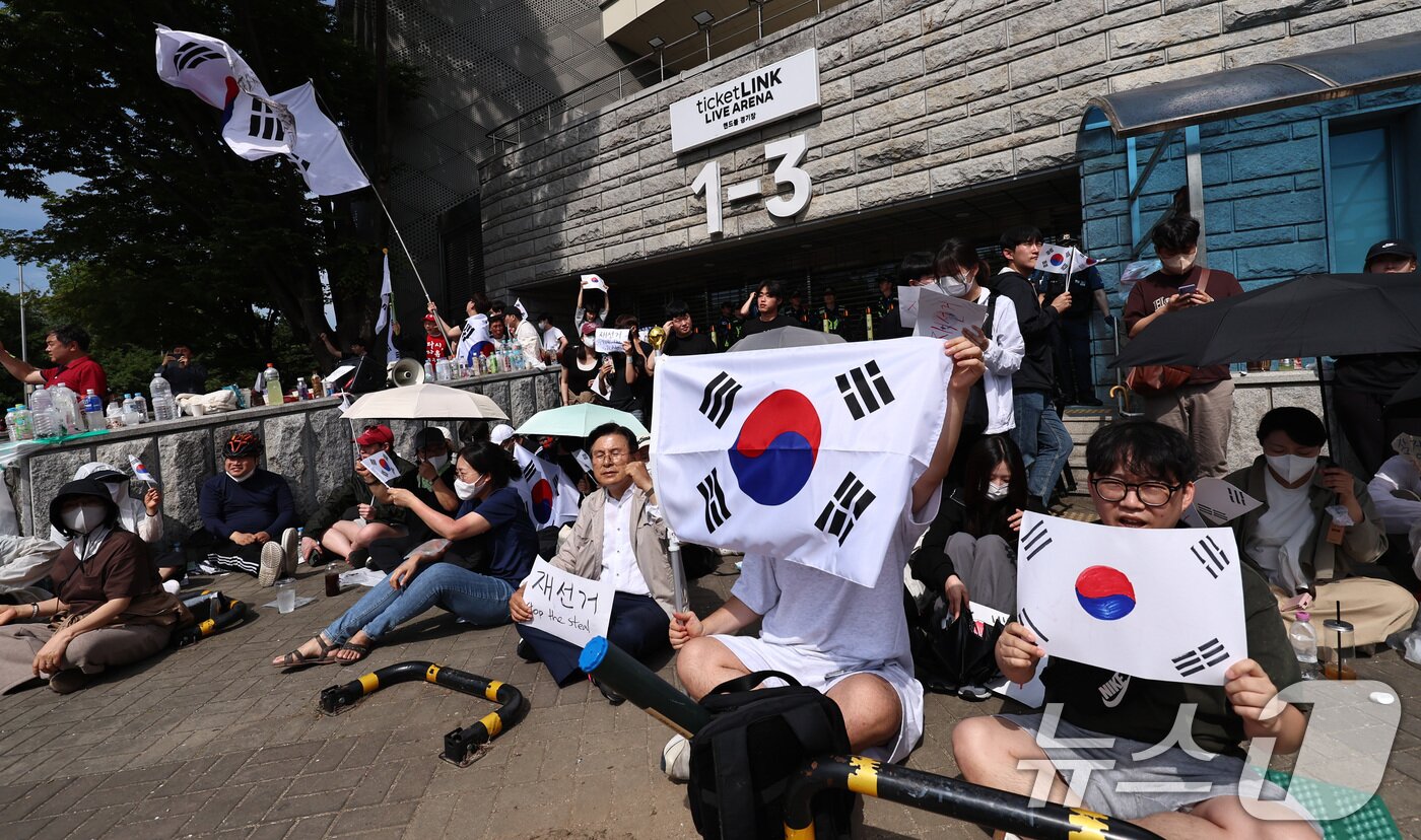 본문 이미지 - 6·3 지방선거 투표용지 부족 사태에 반발한 시민들이 6일 오전 서울 송파구 올림픽공원 핸드볼경기장 개표소 앞에 모여 재선거를 요구하는 구호를 외치고 있다. 2026.6.6 ⓒ 뉴스1 구윤성 기자