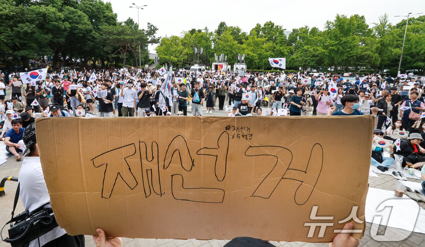 본문 이미지 - 제9회 전국동시지방선거 투표용지 부족 사태에 반발한 시민들이 7일 서울 송파구 올림픽공원 핸드볼경기장 개표소 앞에 모여 재선거를 요구하는 구호를 외치고 있다. 2026.6.7 ⓒ 뉴스1 이호윤 기자