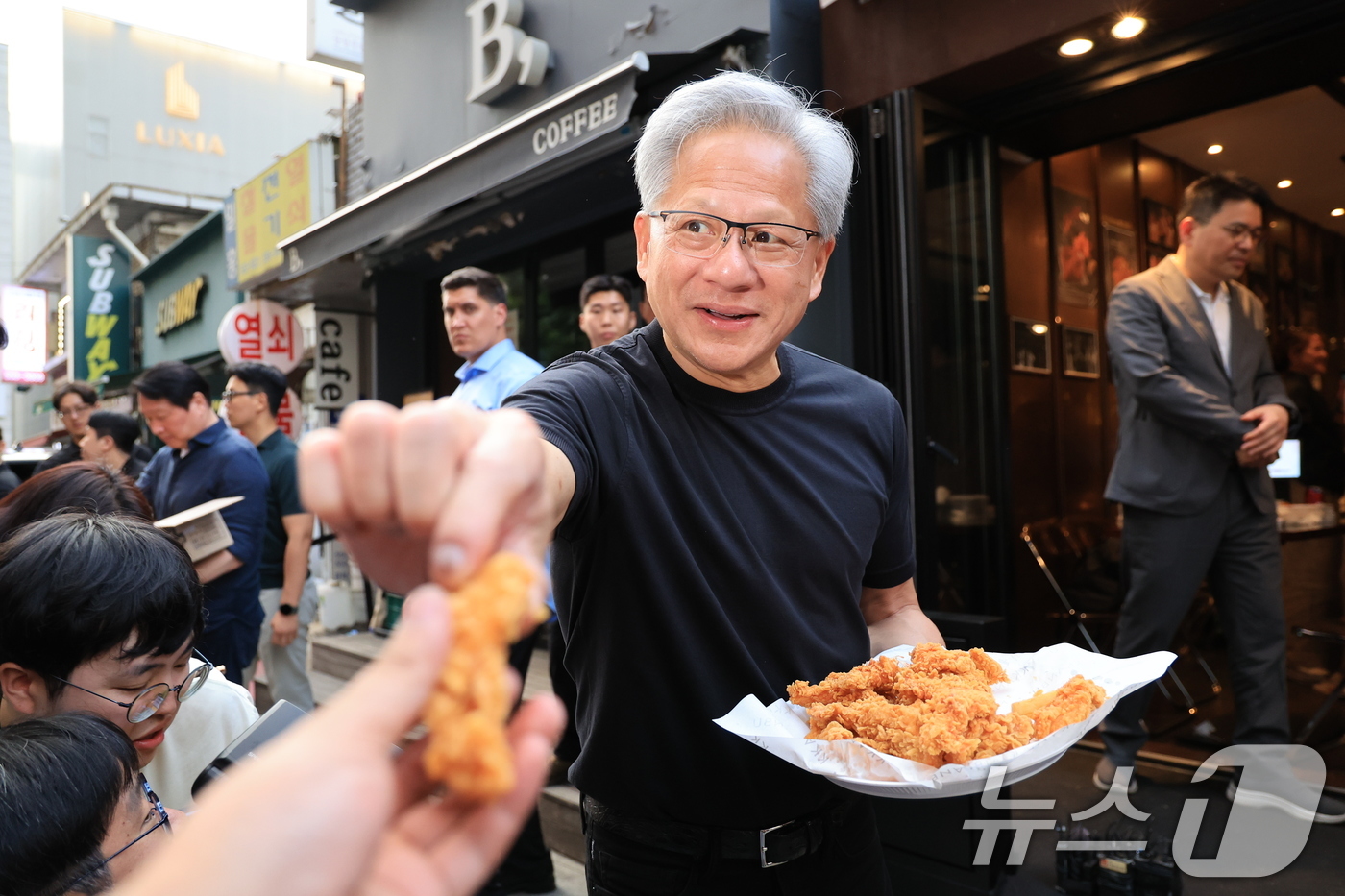 (서울=뉴스1) 이호윤 기자 = 젠슨 황 엔비디아 최고경영자(CEO)가 7일 오후 서울 강남구 깐부치킨 삼성점에서 최태원 SK그룹 회장과 '치맥 회동' 중 시민 및 취재진에게 치킨 …