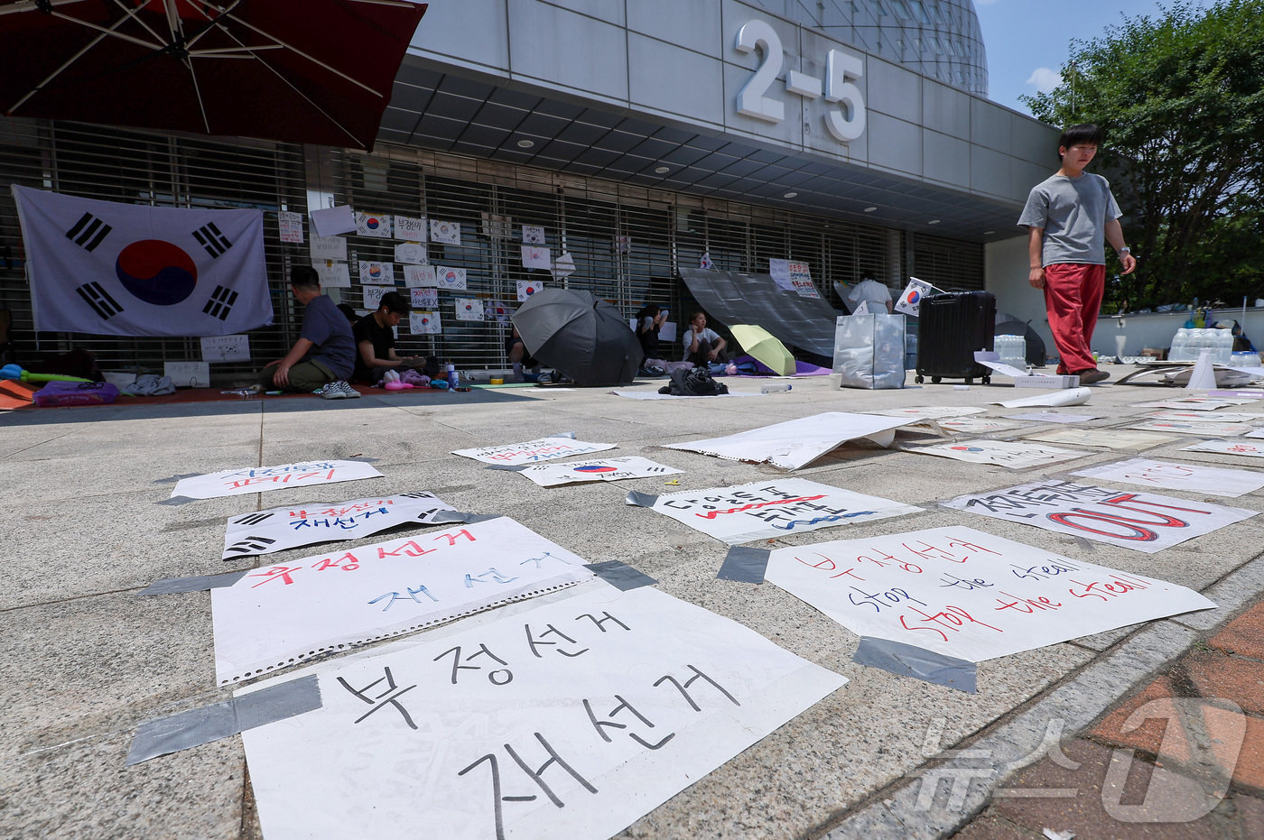 (서울=뉴스1) 김성진 기자 = 제9회 전국동시지방선거 투표용지 부족 사태에 반발한 시민들이 9일 서울 송파구 올림픽공원 핸드볼경기장에 설치된 개표소 앞에 앉아 있다. 2026.6 …