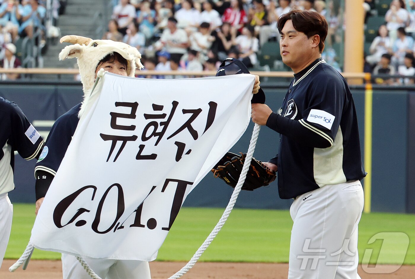 본문 이미지 - 11일 서울 송파구 잠실야구장에서 열린 ‘2026 신한 SOL KBO 올스타전’에서 나눔팀 한화 문현빈이 2회말 '류현진 GOAT'가 적힌 현수막을 들며 마운드로 향하고 있다. 이번 올스타전은 프로야구 원년인 1982년 준공돼 한국 야구 역사와 함께해 온 잠실야구장에서 열리는 14번째이자 마지막 축제로, 리그를 대표하는 별들이 총출동해 고별 무대를 수놓는다. 2026.7.11 ⓒ 뉴스1 김진환 기자