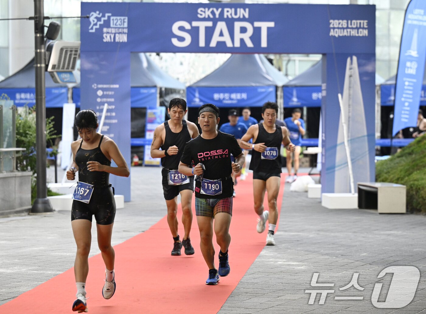본문 이미지 - 12일 오전 서울 송파구 석촌호수와 롯데월드타워 일원에서 열린 '2026 롯데 아쿠아슬론'에서 수영을 마친 참가자들이 수직마라톤을 위해 롯데월드타워로 향해 달리고 있다. (공동취재) 2026.7.12 ⓒ 뉴스1 구윤성 기자