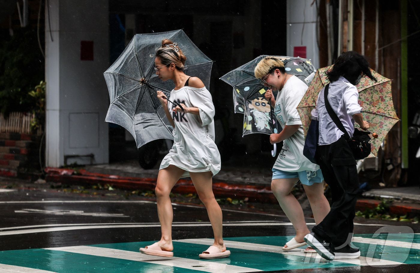 본문 이미지 - 태풍 바비가 대만 북동부 해상을 지나던 11일, 대만 지룽에서 보행자들이 강한 바람과 비를 맞으며 우산을 쓰고 도로를 건너고 있다. 2026.07.11 ⓒ AFP=뉴스1