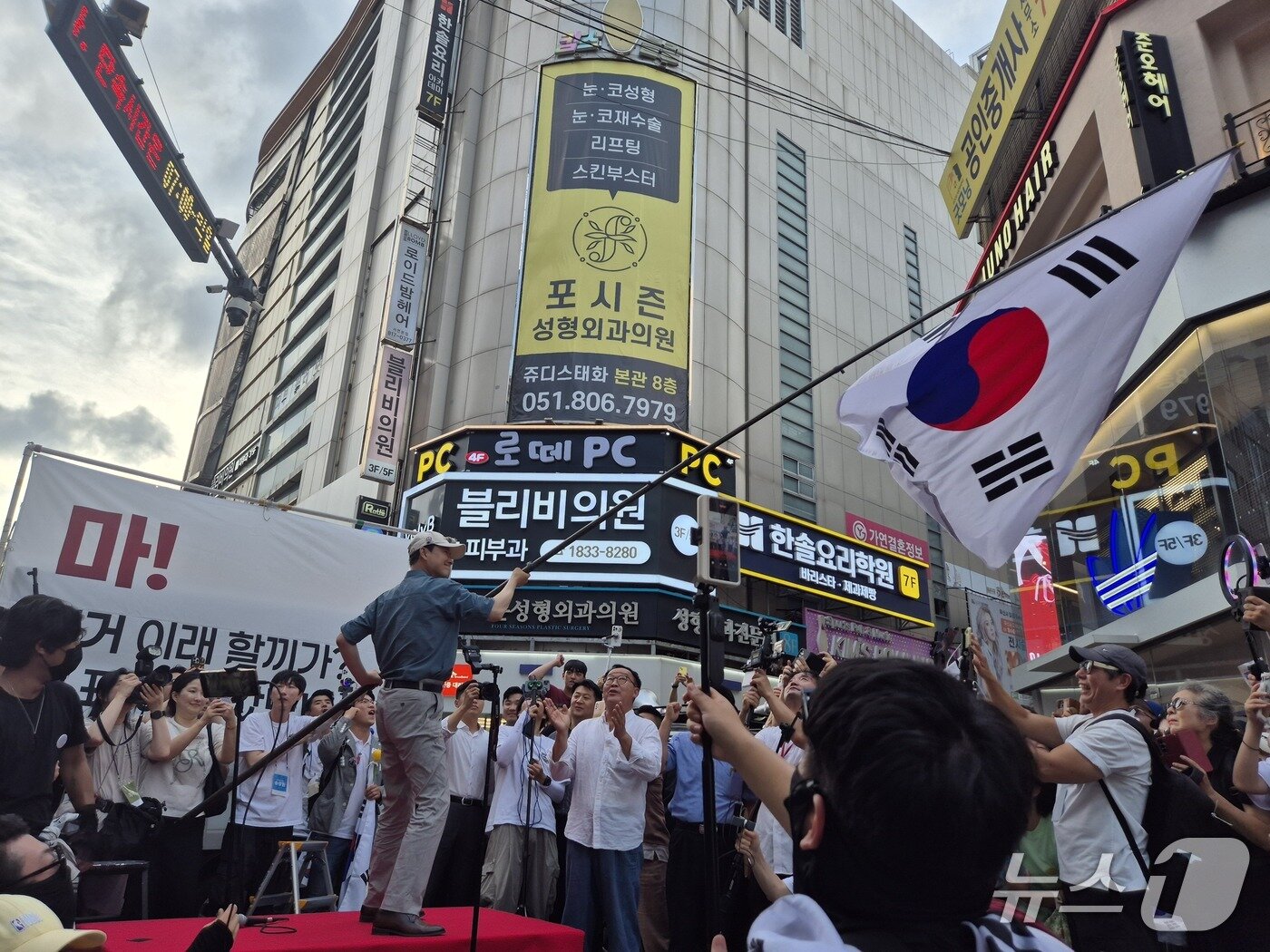 본문 이미지 - 장동혁 국민의힘 대표가 12일 오후 부산 부산진구 서면 하트광장에서 열린 시민운동 현장에 참석해 대형 태극기를 흔들고 있다. 2026.07.12.ⓒ 뉴스1 조유리 기자.