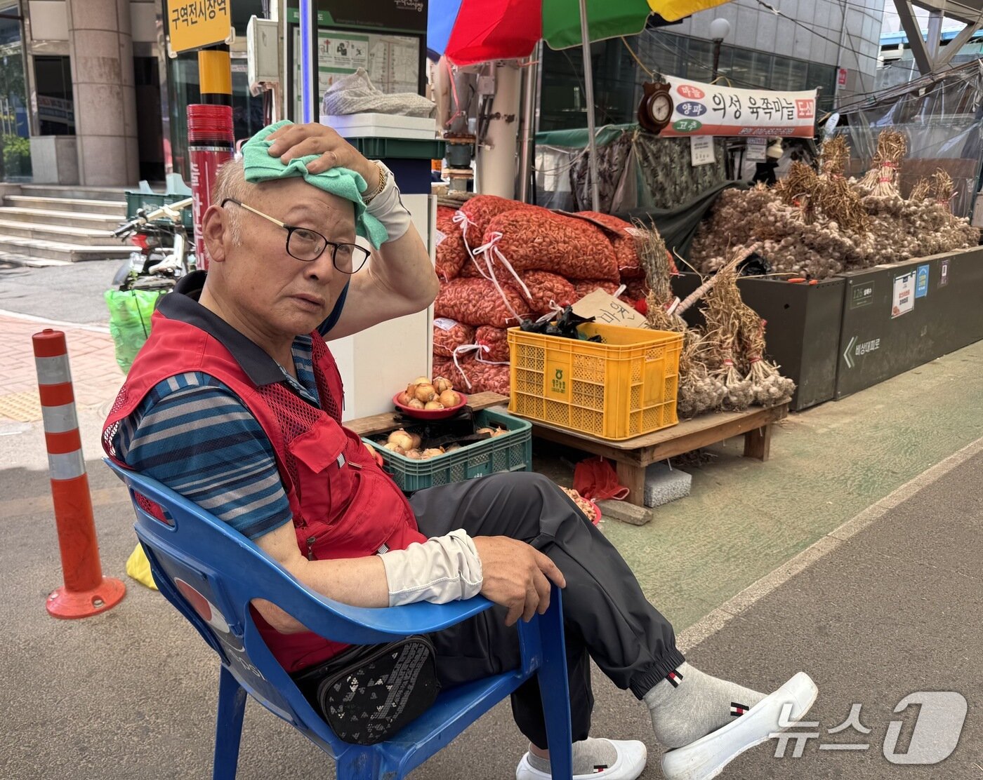 본문 이미지 - 13일 울산 중구 구역전시장에서 한 상인이 젖은 수건으로 더위를 식히고 있다.2026.07.13.ⓒ 뉴스1 김세은 기자