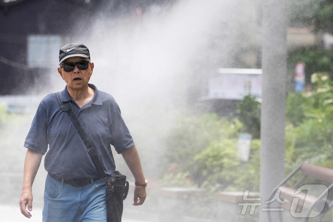 (도쿄 AFP=뉴스1) 권영미 기자 = 14일 일본 도쿄의 무더운 날씨 속에서 한 남성이 쿨링 스프레이(냉각 분사기)에서 뿜어져 나오는 물안개 사이를 걸어가고 있다.2026/07. …