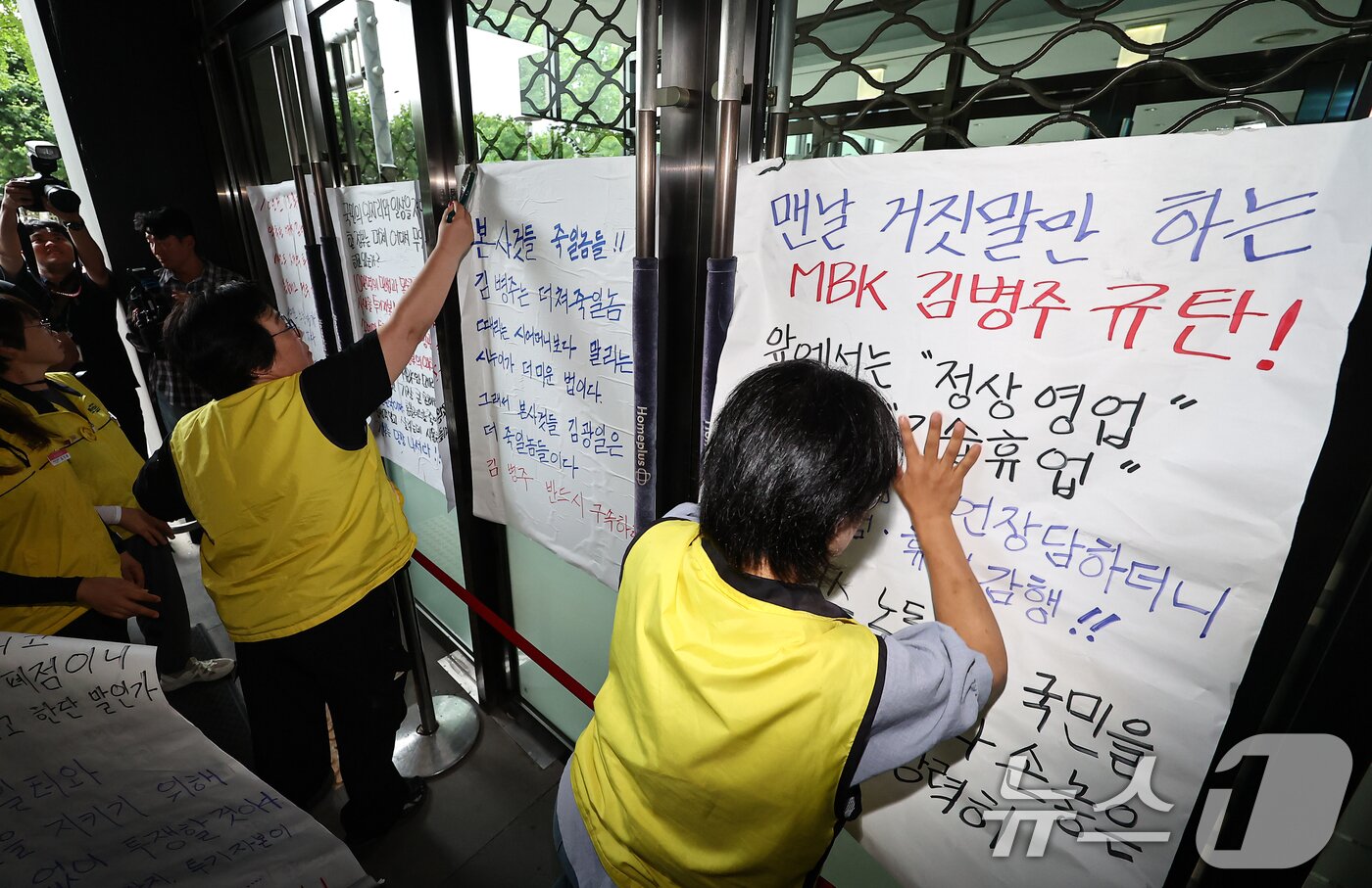 본문 이미지 - 마트산업노조 홈플러스지부 조합원들이 14일 서울 강서구 홈플러스 본사 입구에서 MBK의 일방적 면담 취소 규탄 및 노조 입장발표 기자회견을 마치고 본사에 항의하는 내용을 담은 대자보를 붙이고 있다. 2026.7.14 ⓒ 뉴스1 김도우 기자
