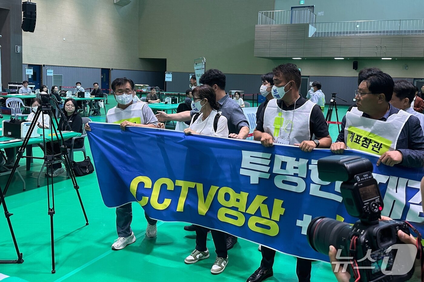본문 이미지 - 15일 충주시장선거 재검표가 진행된 교통대 체육관에서 맹정섭 후보 측 참관인들이 현수막을 펼친 채 투표지 보관상자 이동을 저지하고 있다.2026.7.15/뉴스1 ⓒ 뉴스1 윤원진 기자