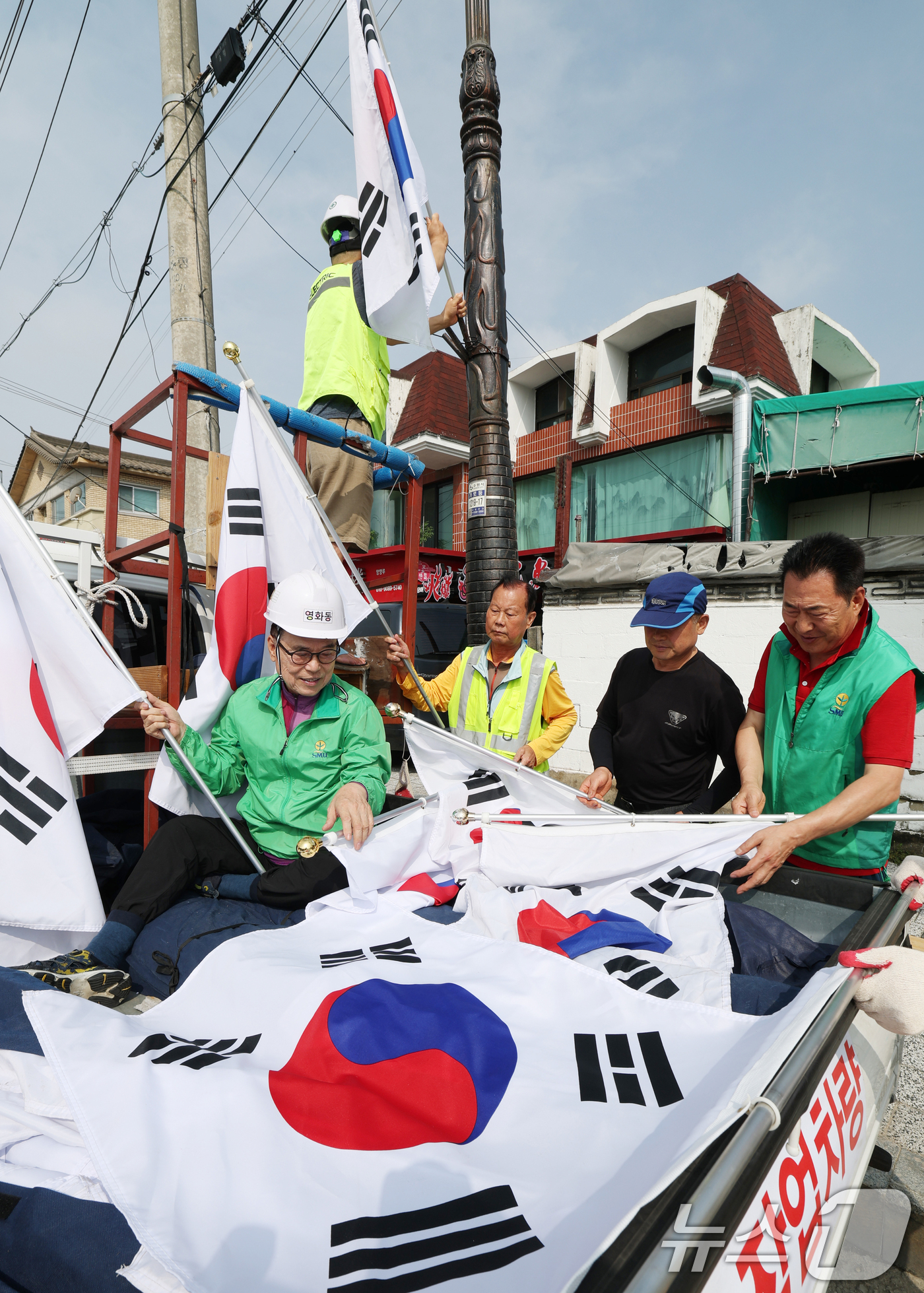 (수원=뉴스1) 김영운 기자 = 제78주년 제헌절을 하루 앞둔 16일 경기 수원시 장안구 관내에서 영화동 새마을지도자협의회 회원들이 태극기를 게양하고 있다.이날 게양한 태극기는 장 …