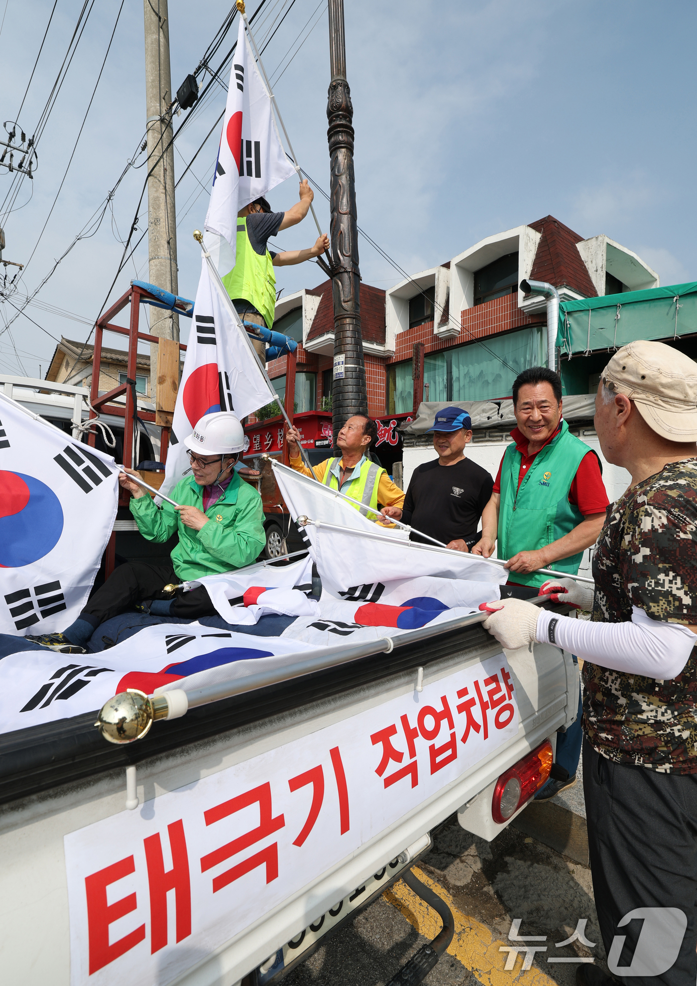 (수원=뉴스1) 김영운 기자 = 제78주년 제헌절을 하루 앞둔 16일 경기 수원시 장안구 관내에서 영화동 새마을지도자협의회 회원들이 태극기를 게양하고 있다.이날 게양한 태극기는 장 …