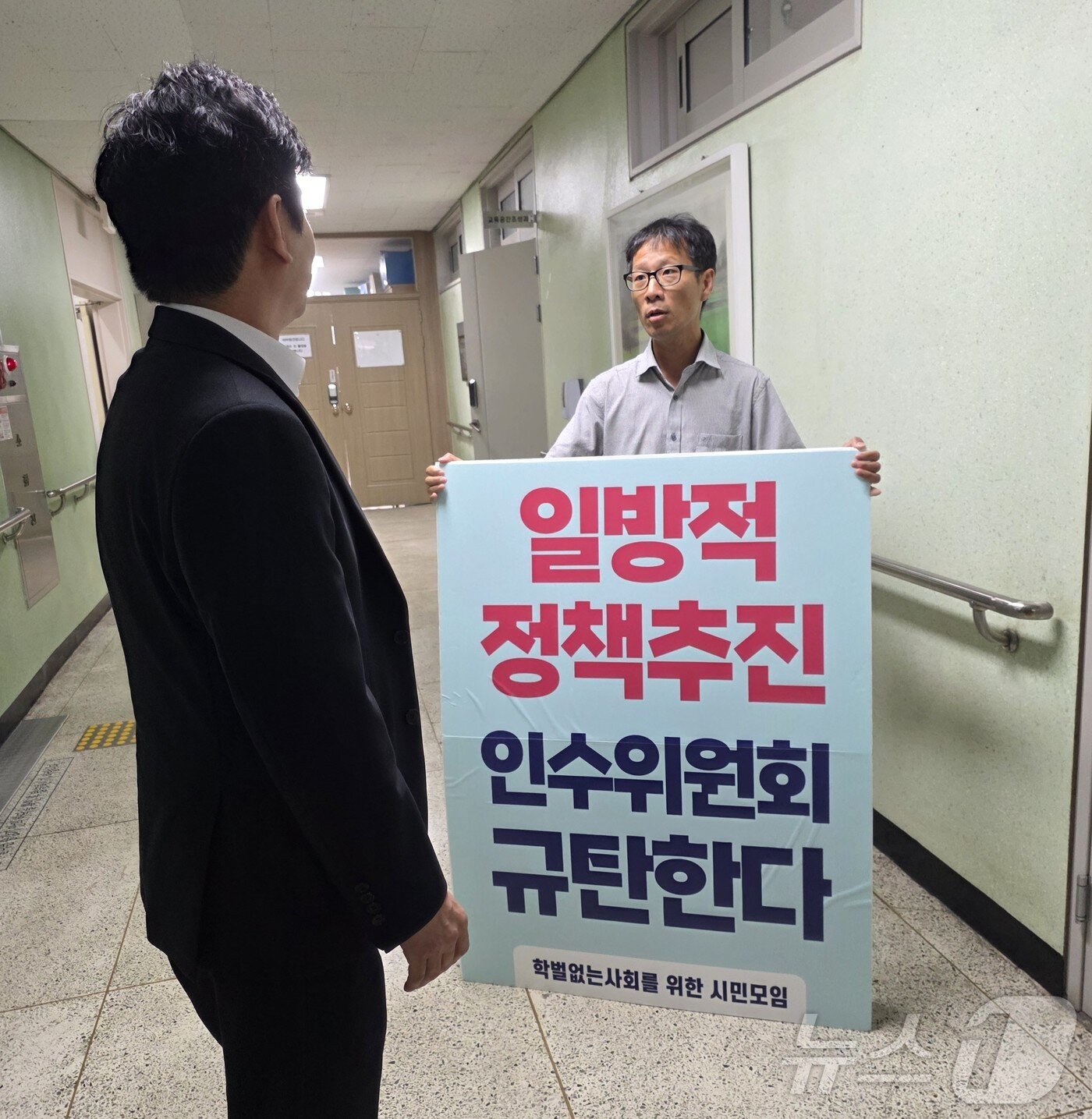 본문 이미지 - 박고형준 학벌없는사회를 위한 시민모임 상임활동가가 16일 전남광주특별시교육청 광주청사에서 K-교육특별시 준비위 기자회견을 앞두고 피켓을 들고 항의하고 있다. 2026.7.16 ⓒ 뉴스1 서충섭 기자